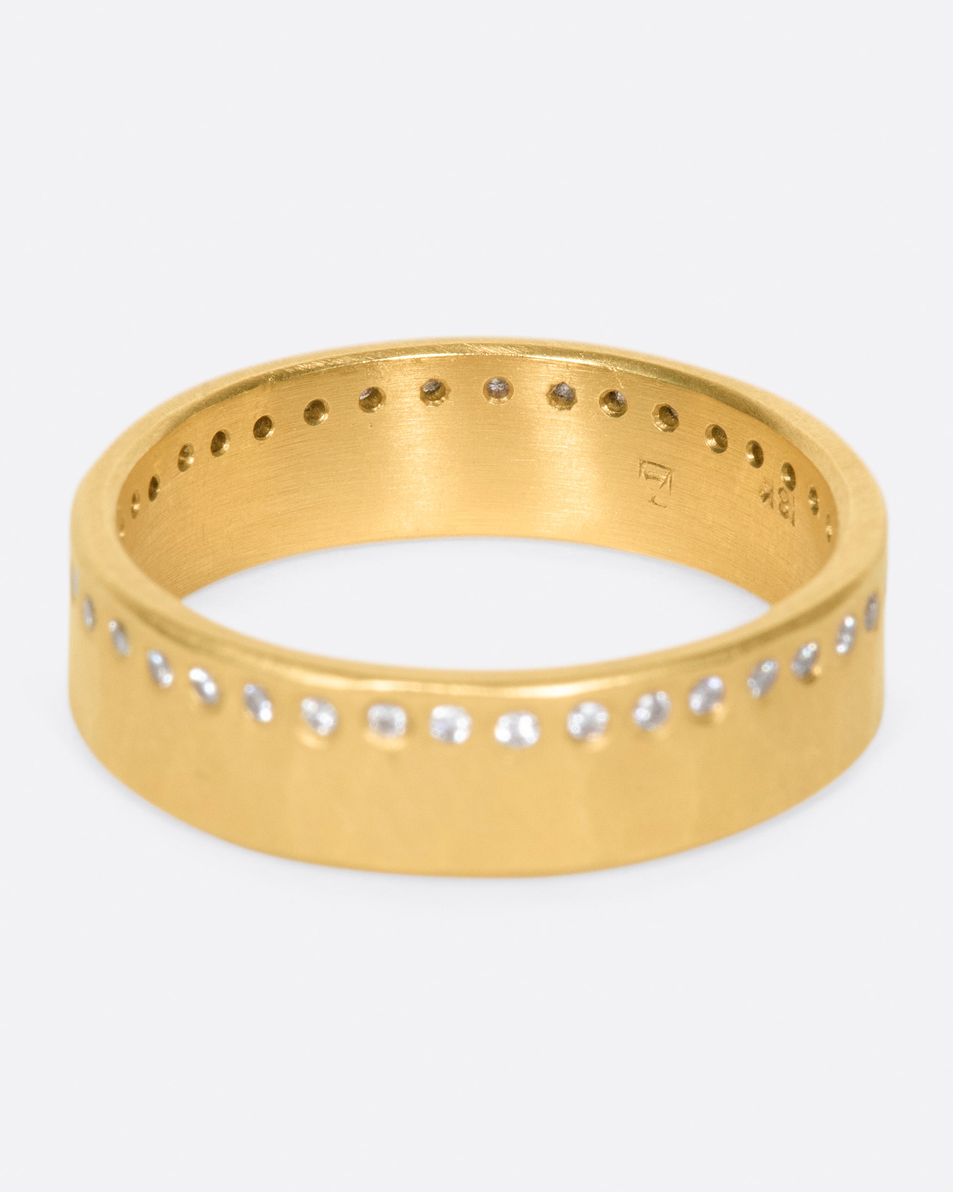 A hammered, matte gold band with a line of round diamonds all the way around.