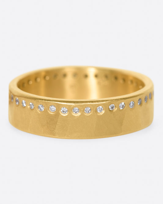 A hammered, matte gold band with a line of round diamonds all the way around.