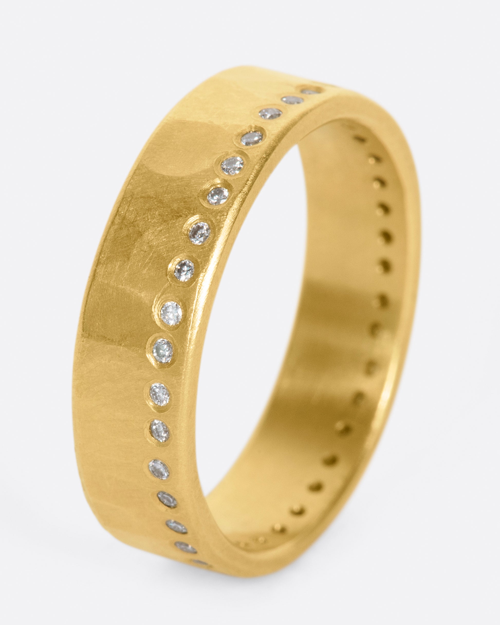 A hammered, matte gold band with a line of round diamonds all the way around.