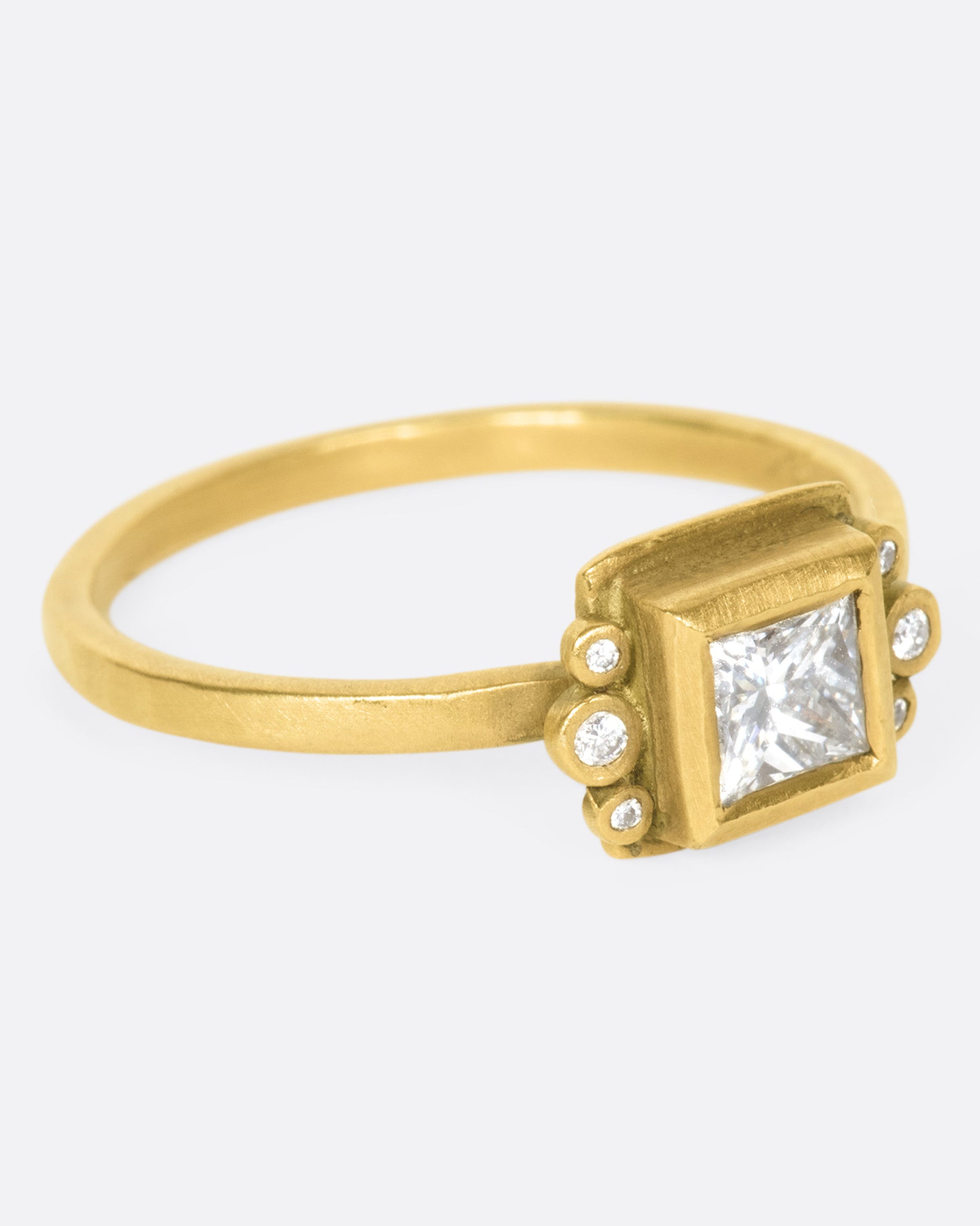 A square diamond in a matching bezel with three round diamonds on either side.