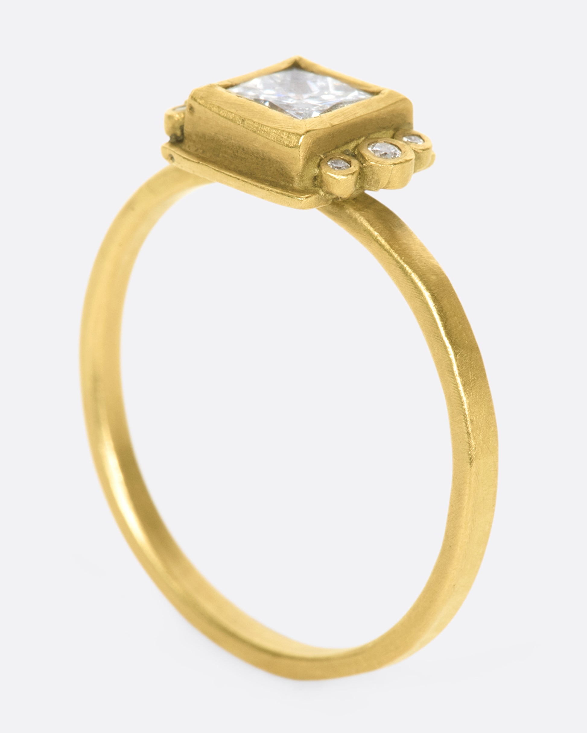 A square diamond in a matching bezel with three round diamonds on either side.