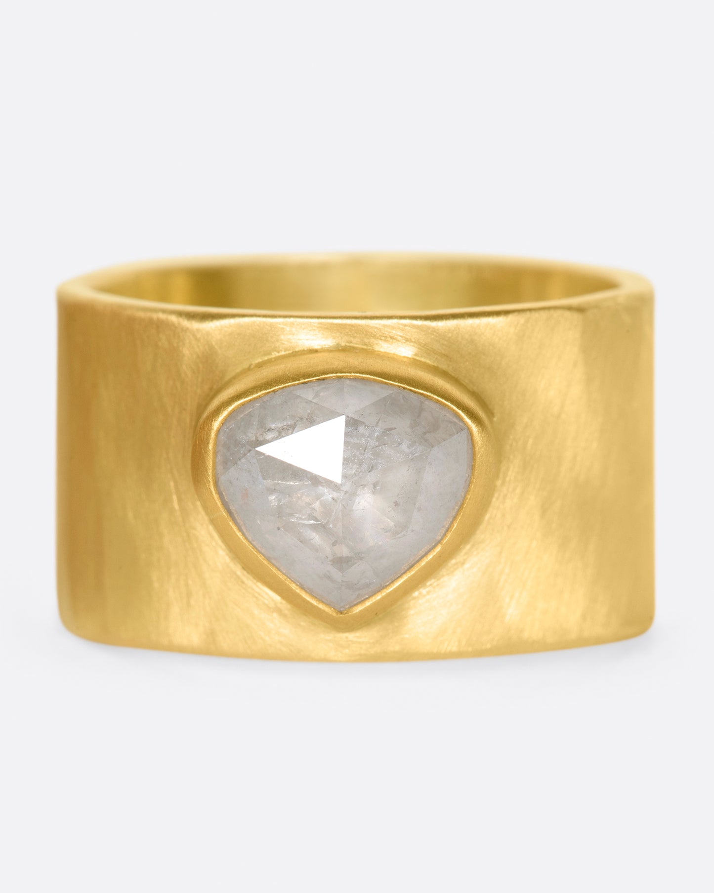 A wide, matte, hammered band with a rose cut gray diamond embedded in a high karat gold setting.