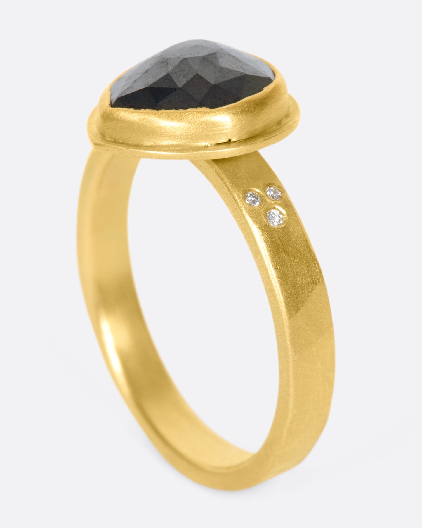 A faceted, pear shaped black diamond in a 22k gold setting with white diamond accents.