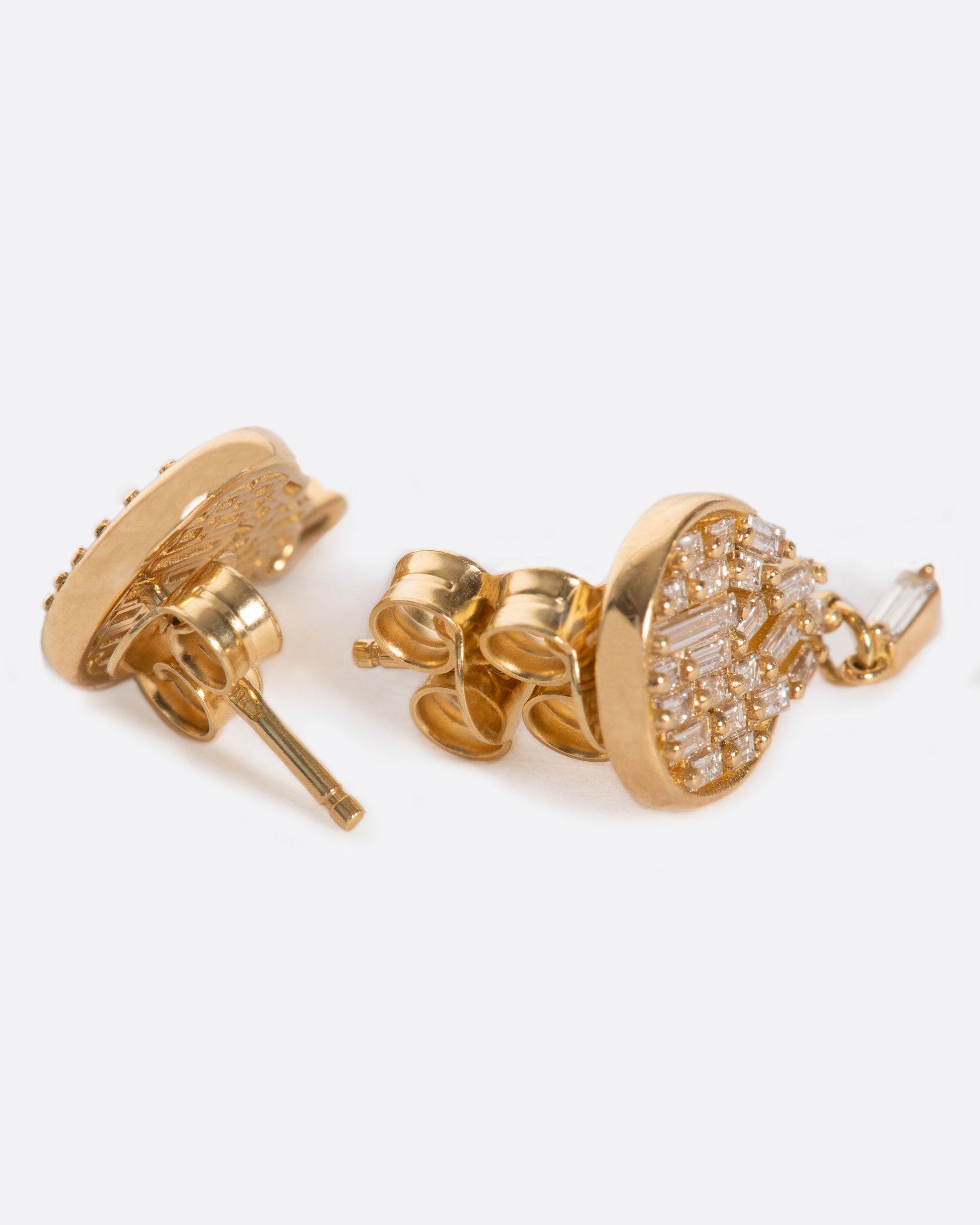 A pair of round stud earrings dripping with diamond baguettes.