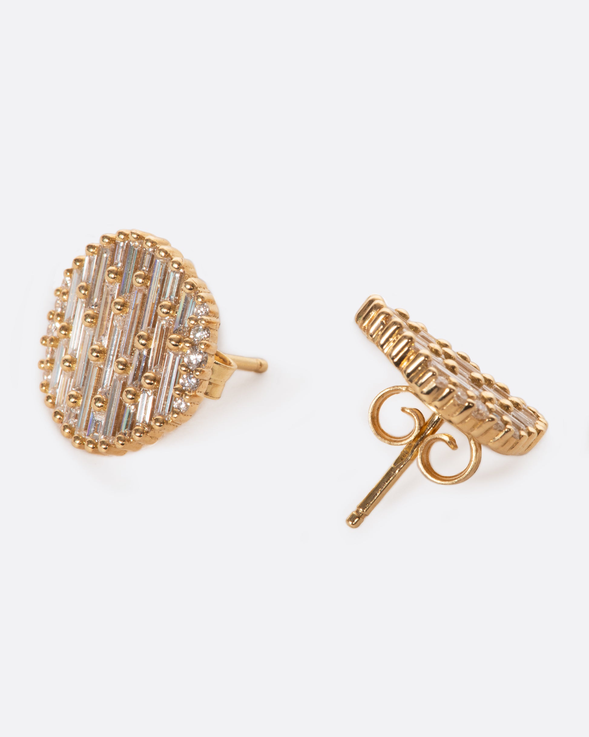 A pair of round, slightly concave stud earrings covered in baguette diamonds.