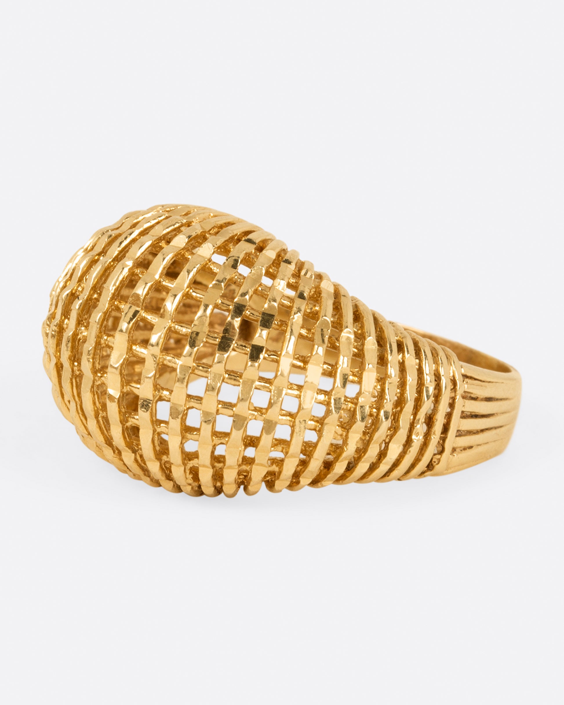 A woven yellow gold dome ring, shown from the side.