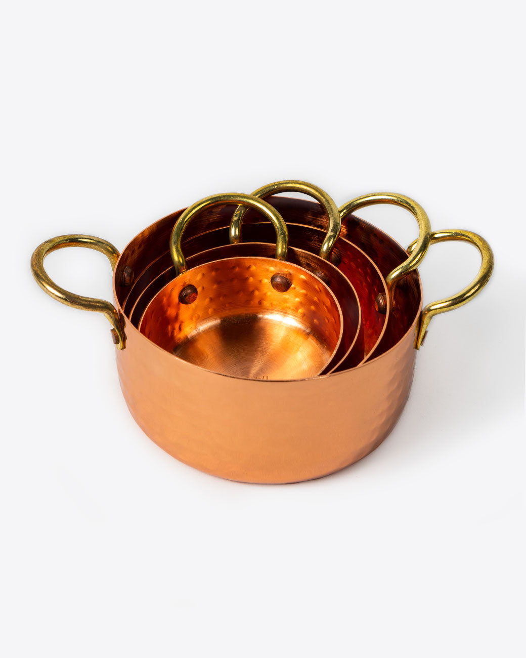 Set of four hammered copper measuring cups, stacked together.