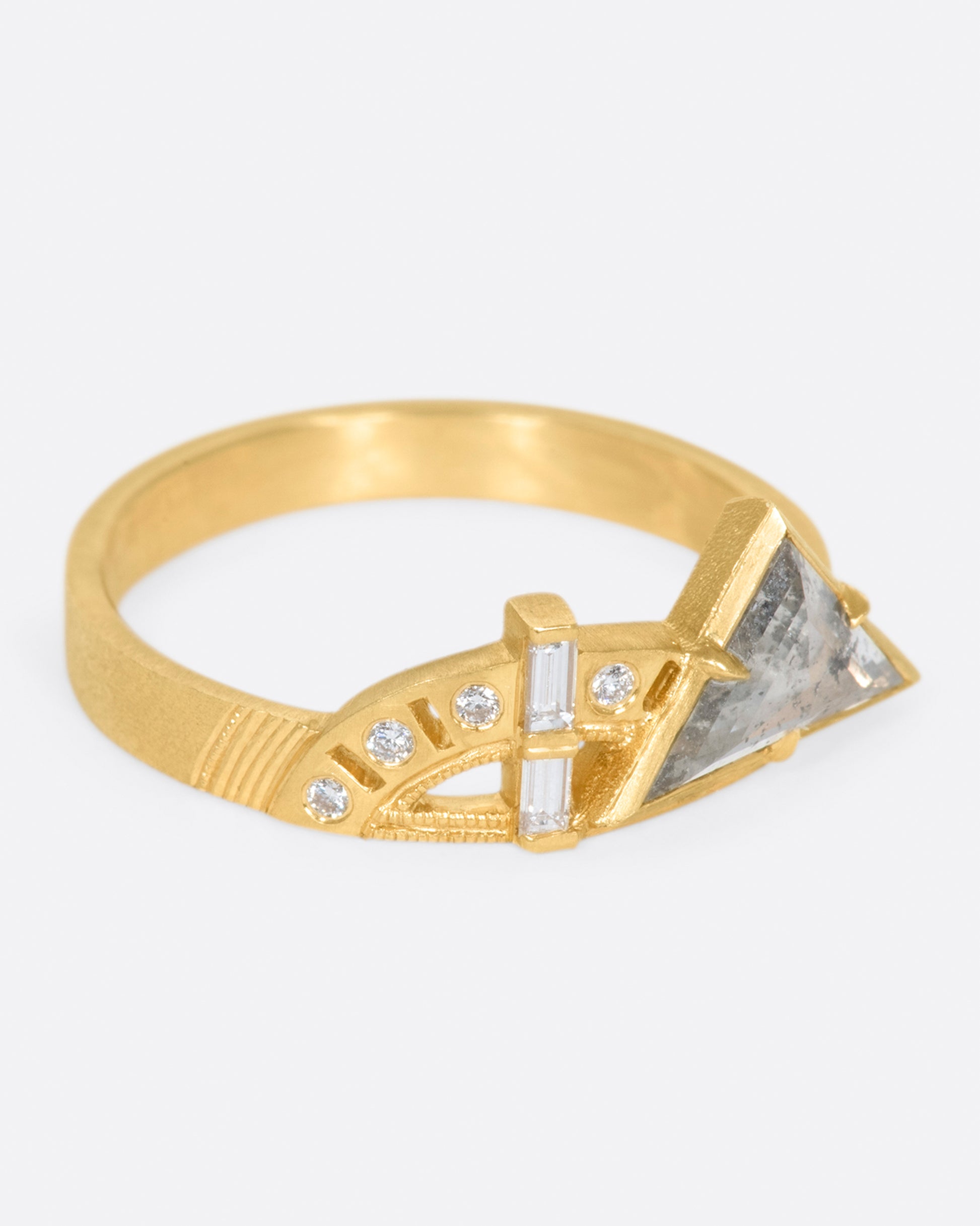 A wide flat band with a salt & pepper trillion cut diamond, gold arches, and round diamonds at its center.