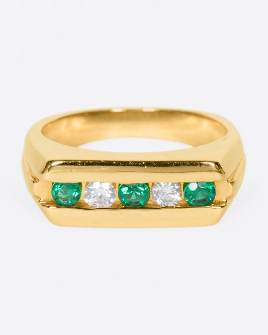 The face of this ring features five channel set stones; three emeralds and two diamonds.