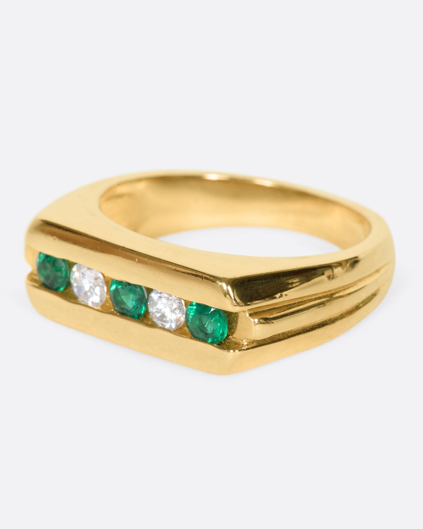 The face of this ring features five channel set stones; three emeralds and two diamonds.