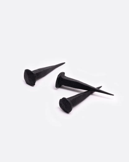 A group of three flat head iron nails. Shown lying on their sides.