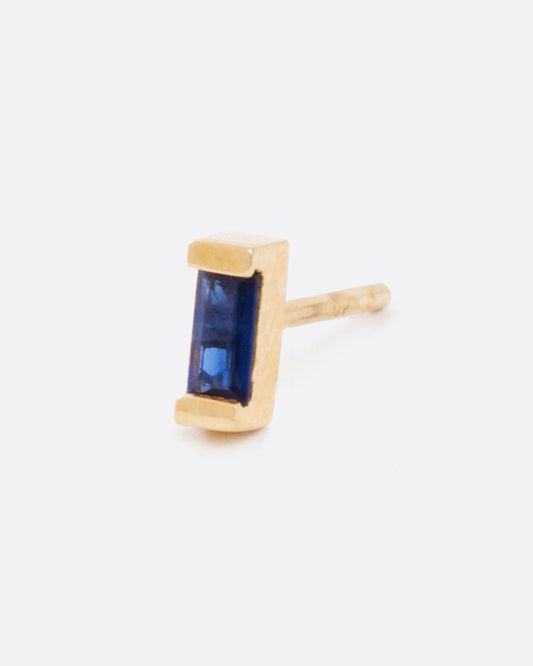 a single earring with a small blue sapphire baguette set in yellow gold