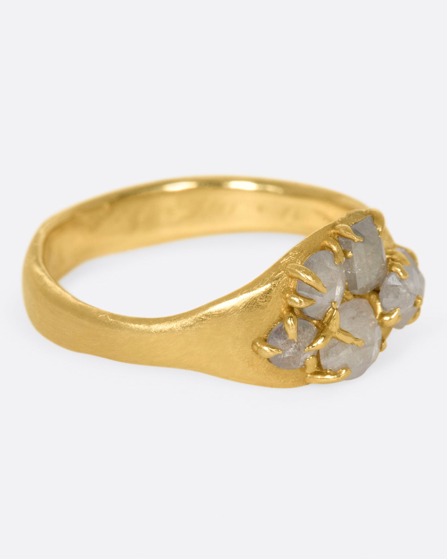 A yellow gold ring with a cluster of prong set gray diamonds on its face.