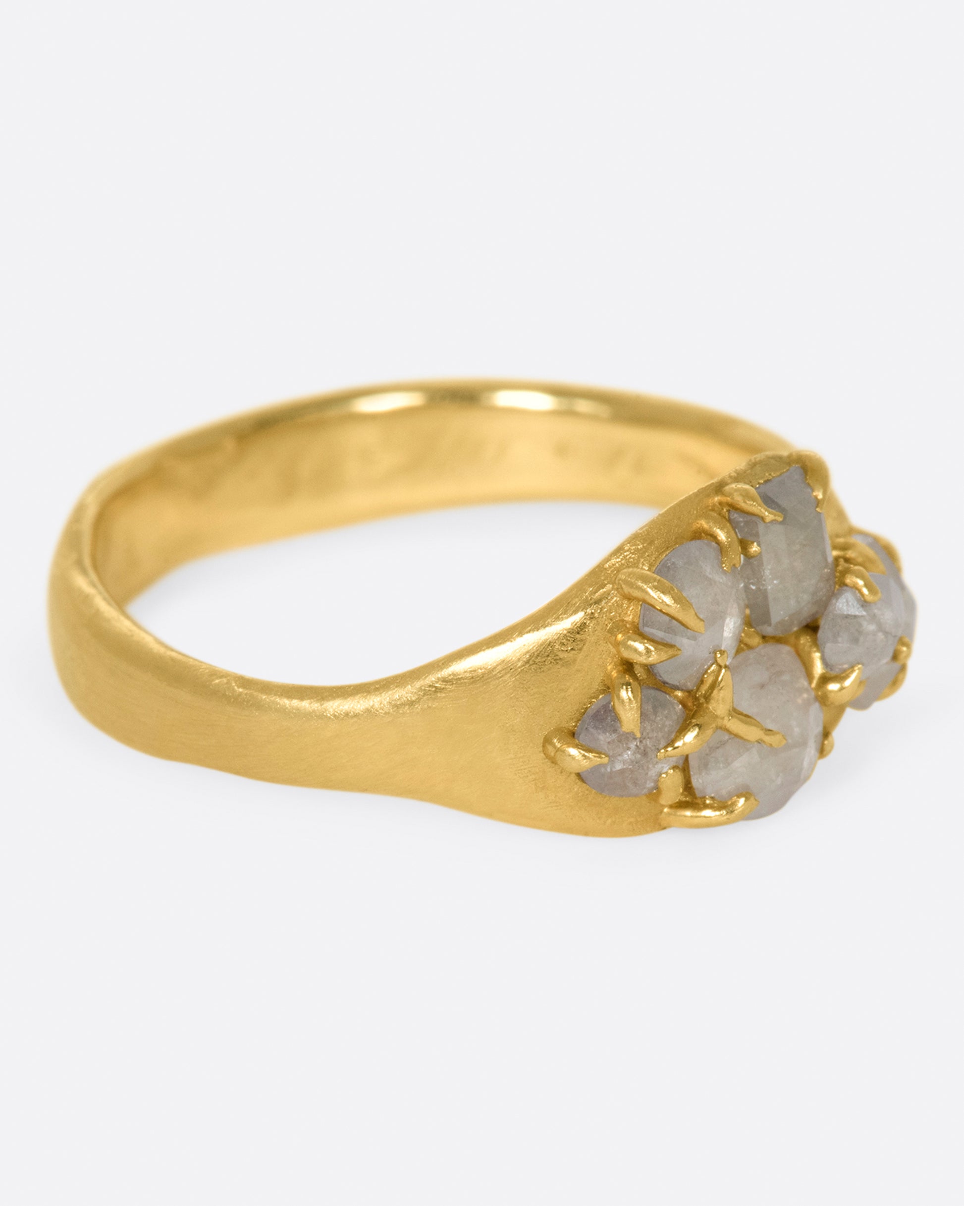 A yellow gold ring with a cluster of prong set gray diamonds on its face.