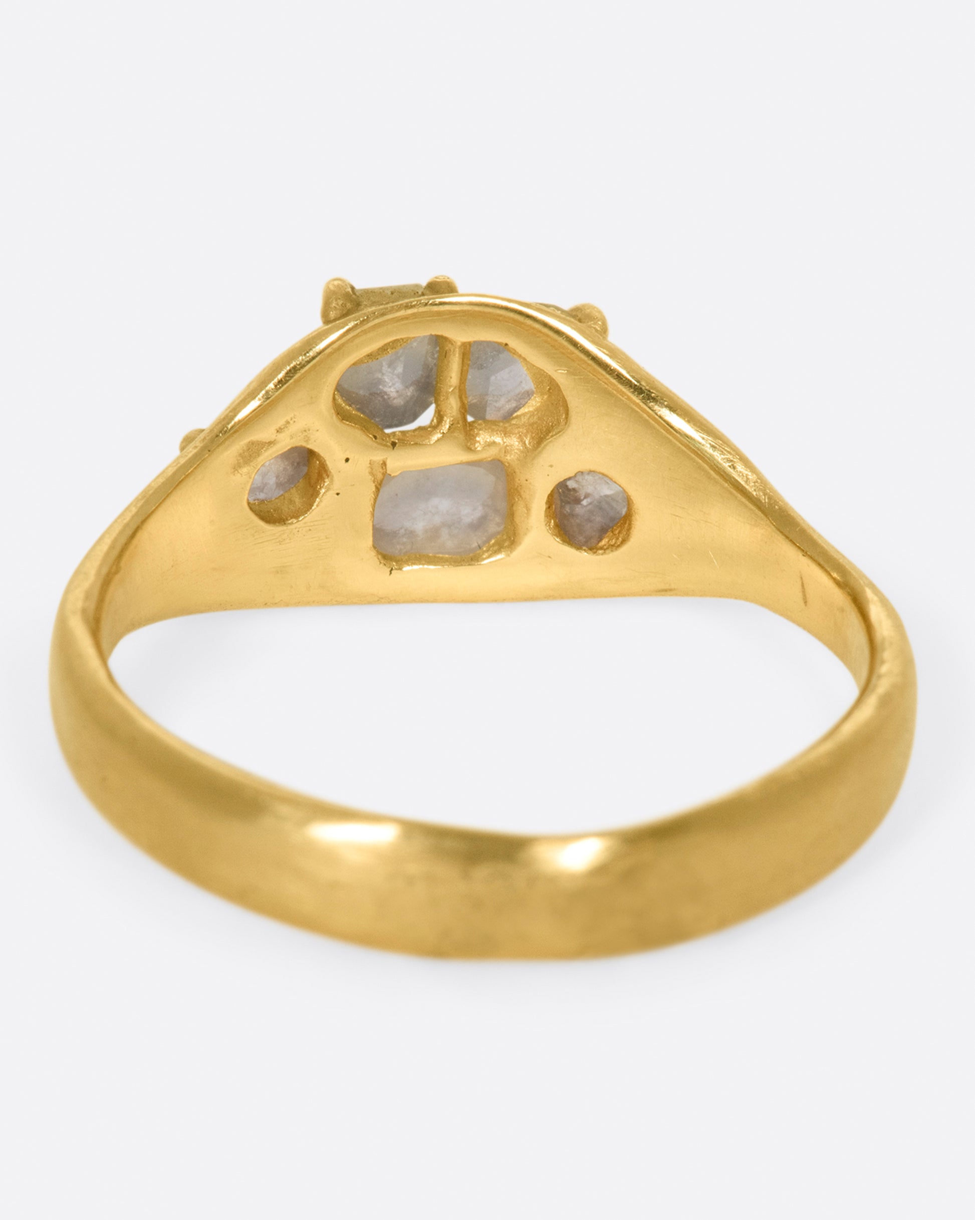 A yellow gold ring with a cluster of prong set gray diamonds on its face.