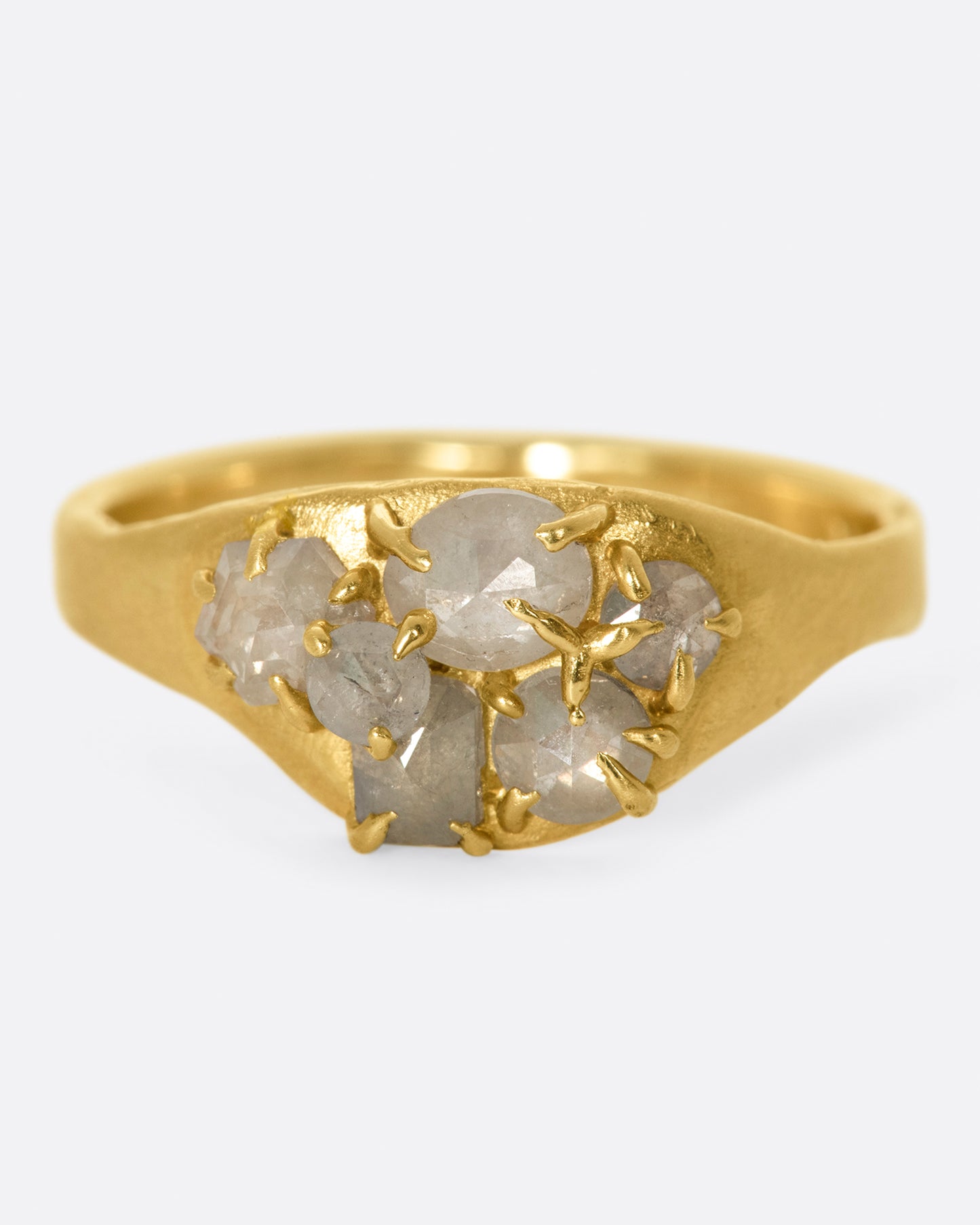 A yellow gold ring with a cluster of prong set gray diamonds on its face.