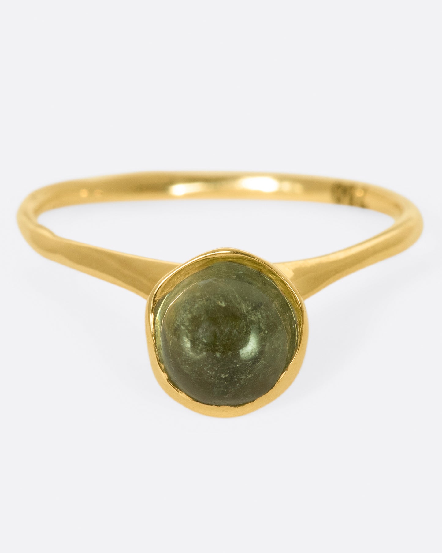 A sage-y green tourmaline cabochon is set in a bezel setting atop this ring.