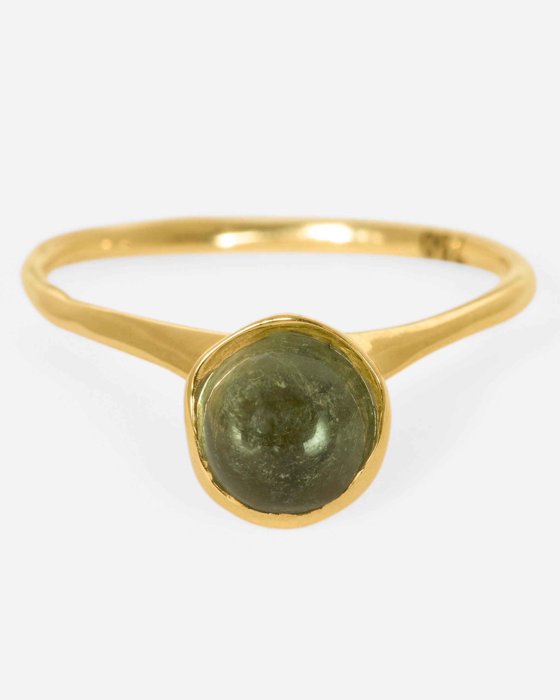 A sage-y green tourmaline cabochon is set in a bezel setting atop this ring.