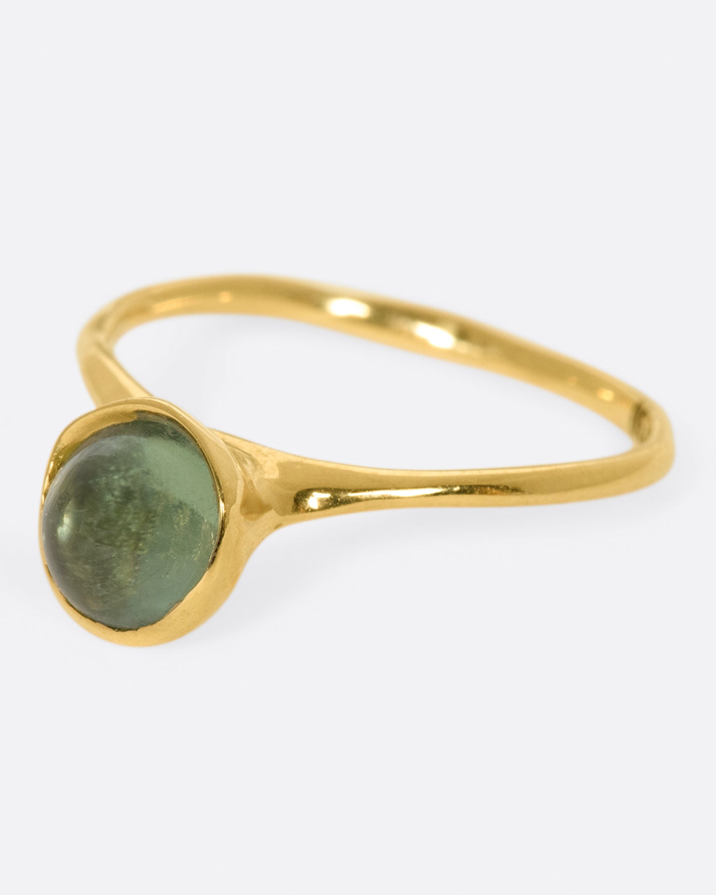 A sage-y green tourmaline cabochon is set in a bezel setting atop this ring.