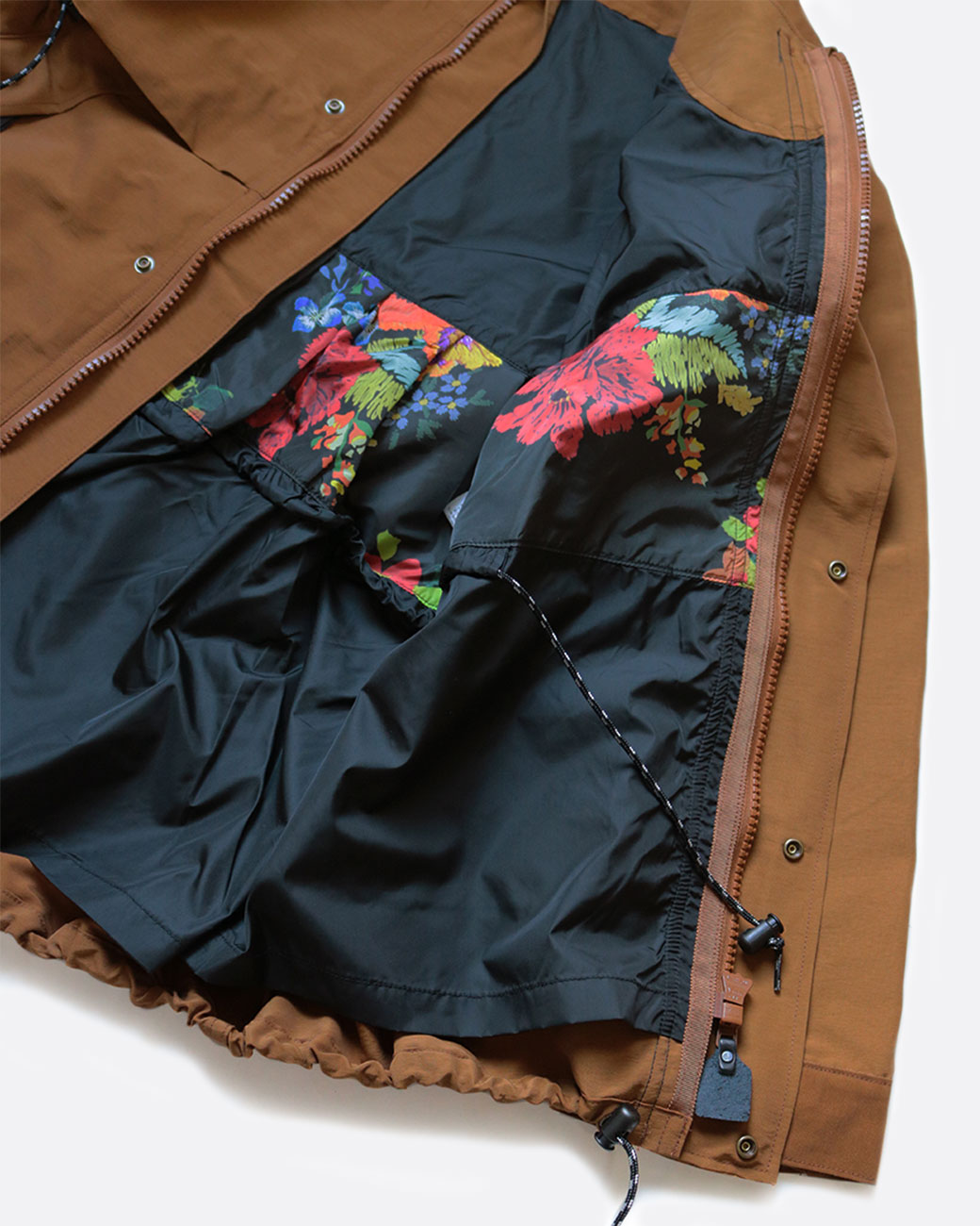 A brown parka with a zipper front, snap buttons, black toggles, and black and floral lining. Shown open from the front.