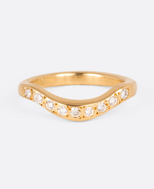 A curved yellow gold band with nine round white diamonds, shown from the front.