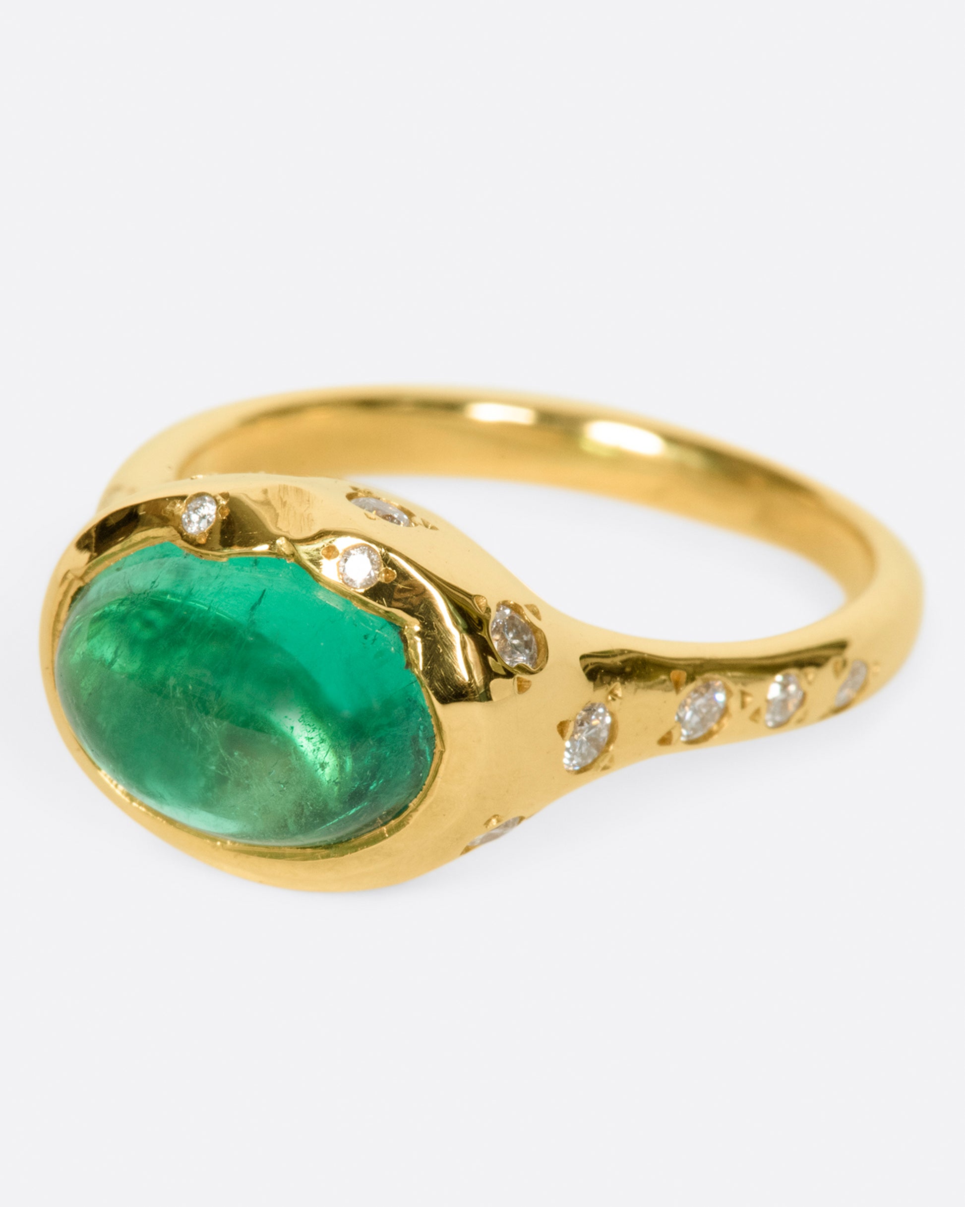 A bright green emerald cabochon sits at the center of this signet style ring.