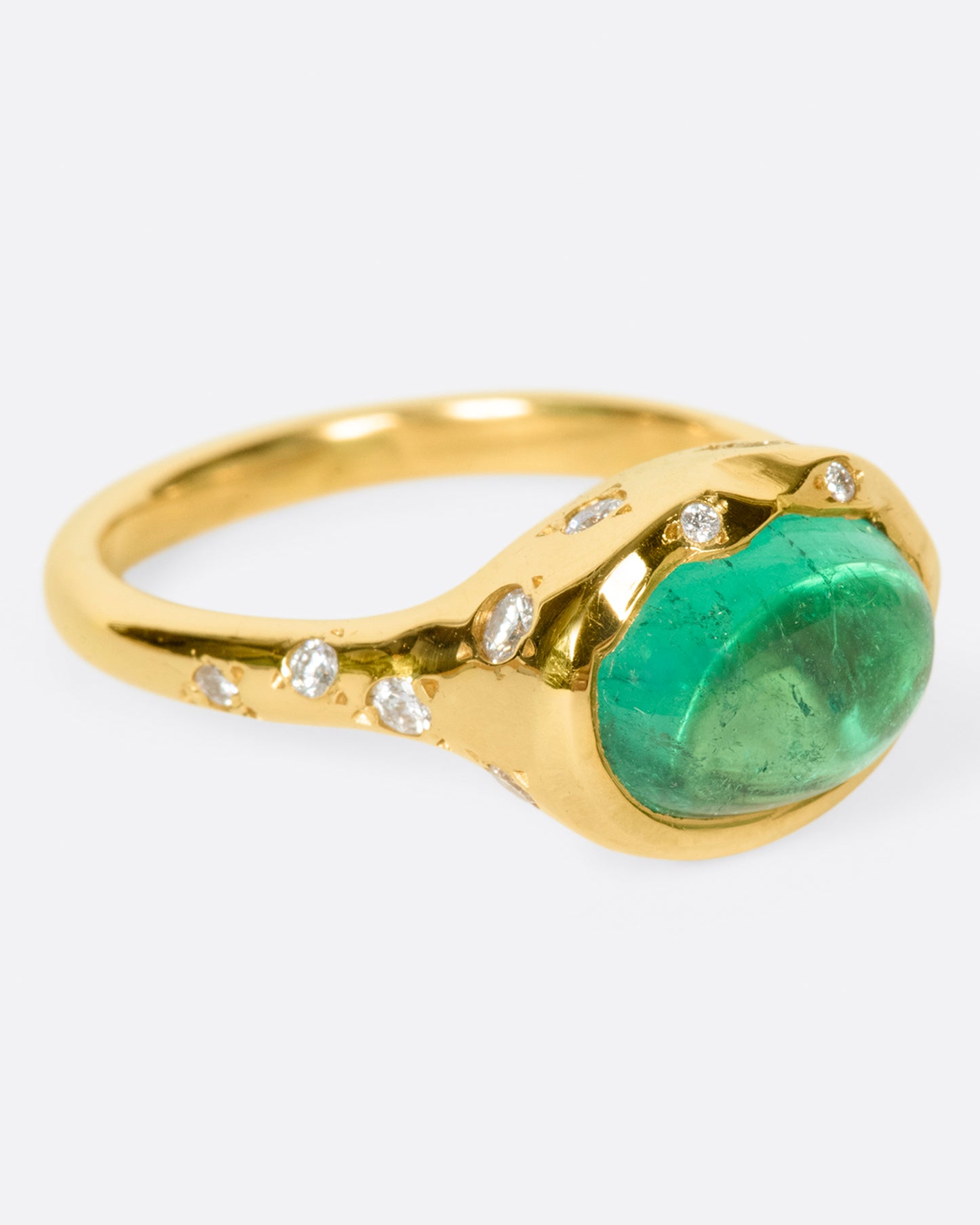 A bright green emerald cabochon sits at the center of this signet style ring.