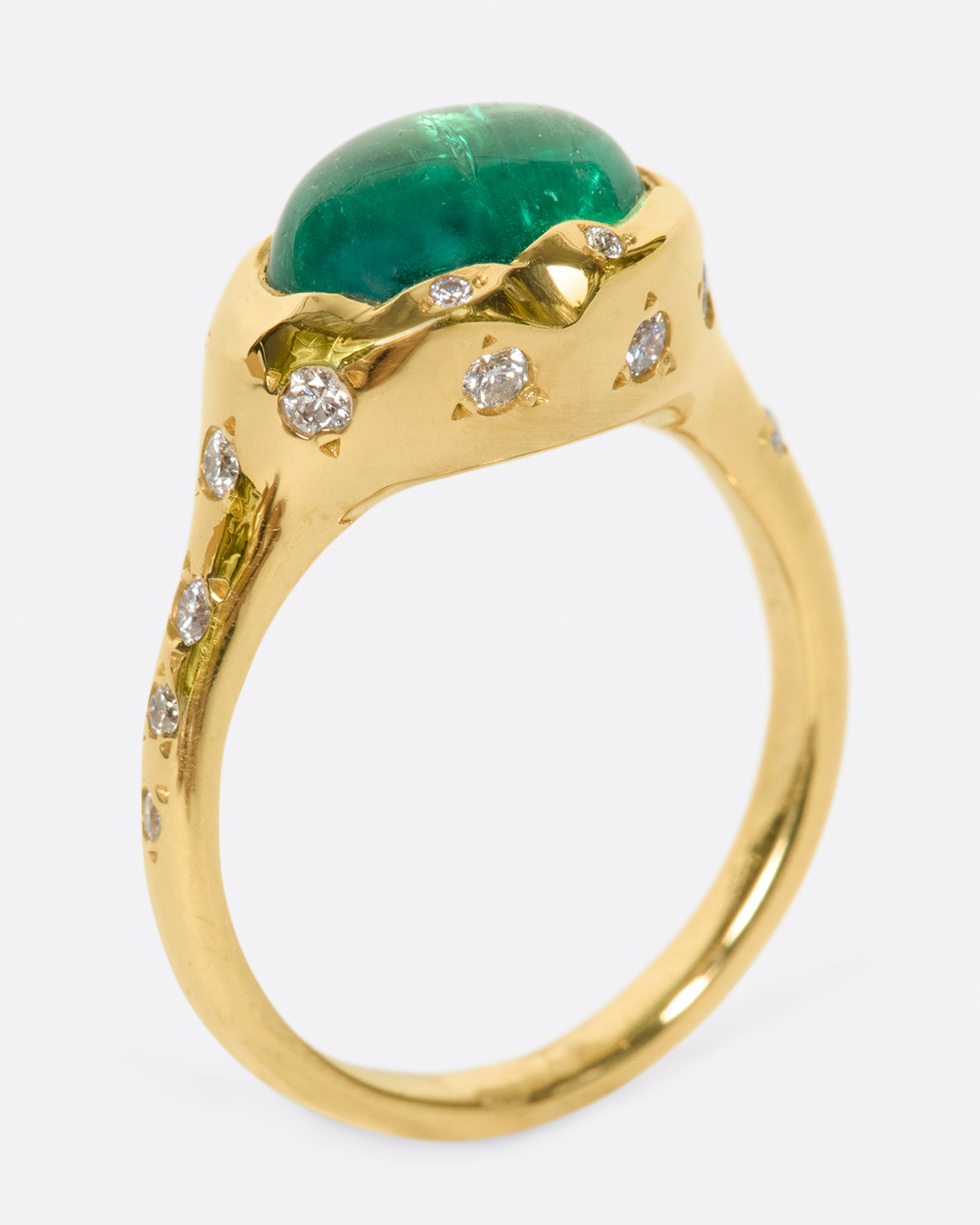 A bright green emerald cabochon sits at the center of this signet style ring.