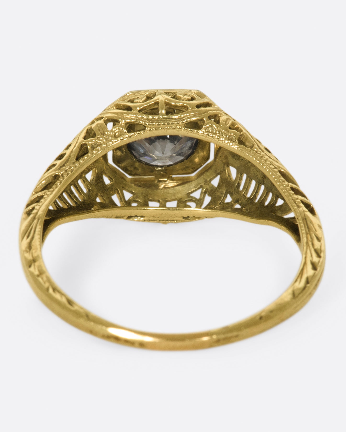 A filigree-covered signet ring with a champagne diamond at its center, set in a white gold bezel.