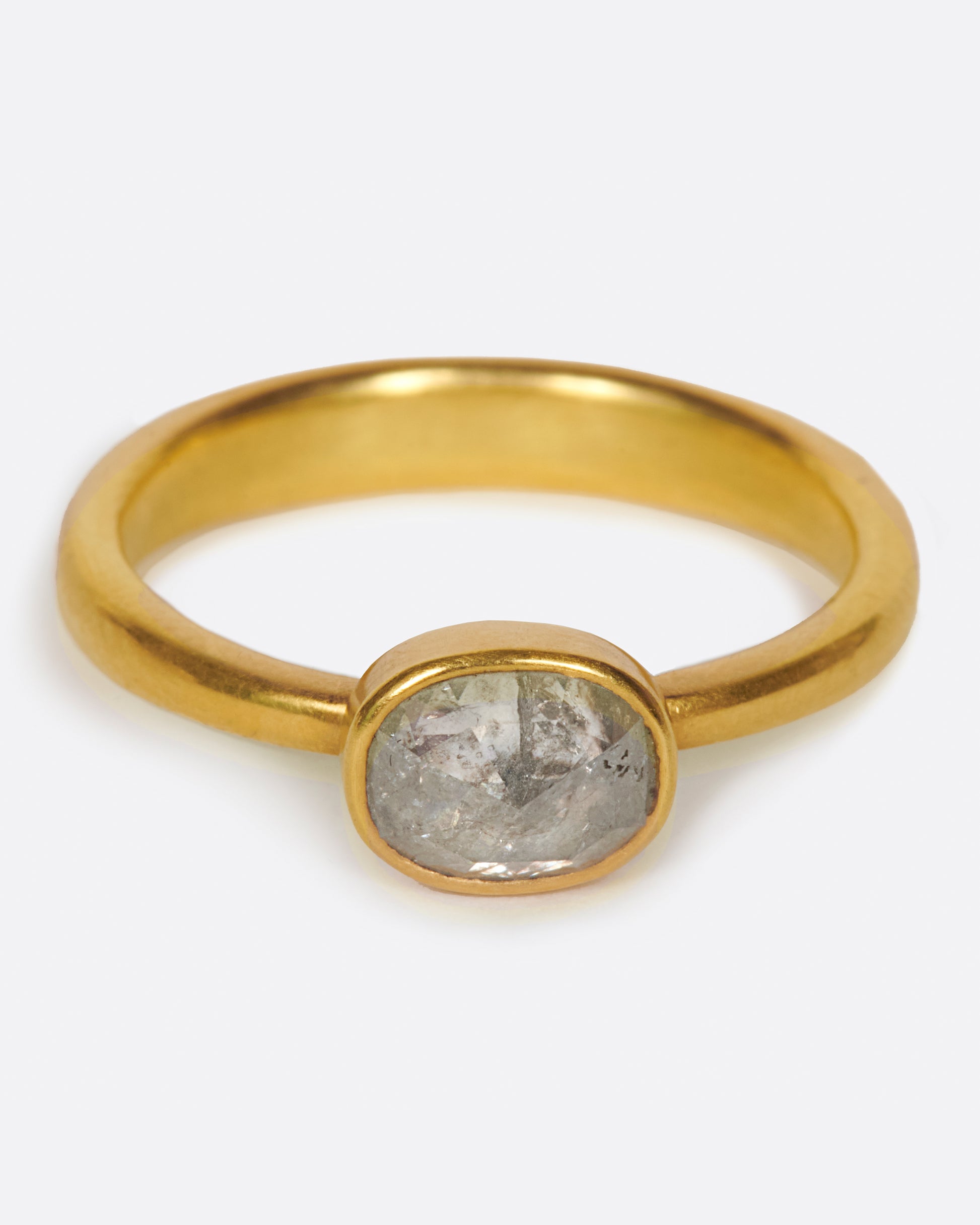 A pale grey, rose cut, oval diamond. Set horizontally on a simple, solid gold band, for a comfortably luxurious and unique design.