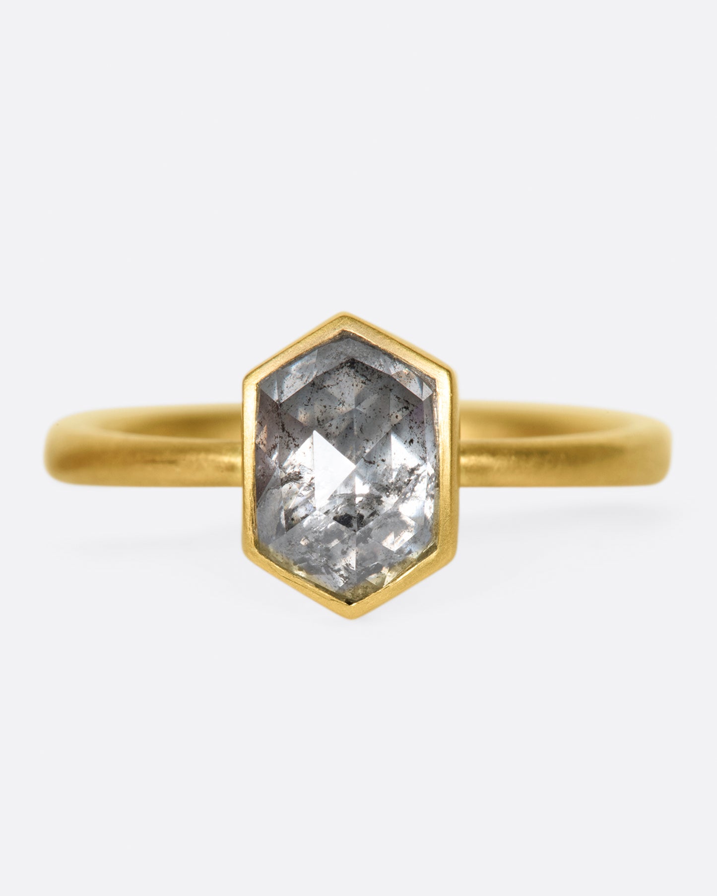 A salt and peppery hexagonal diamond shines in a bezel setting atop this ring.