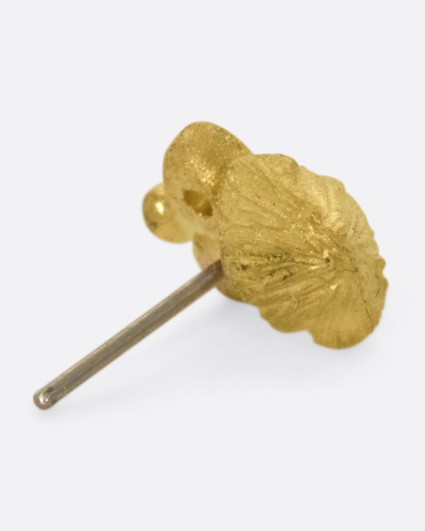 Matte gold and hand carved, this little fungus remains subtle on the ear.