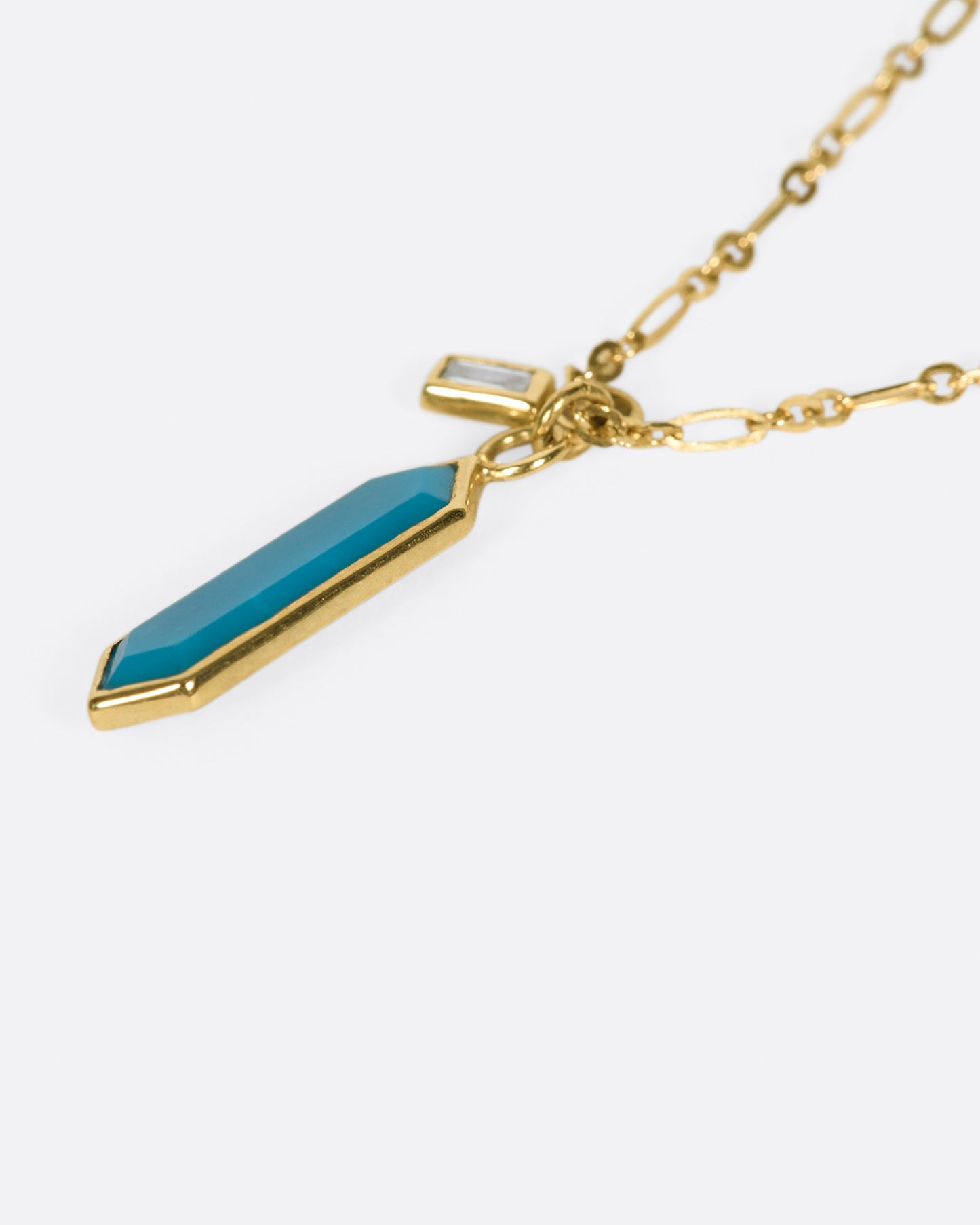 An elongated link chain necklace with a hexagonal turquoise pendant and a baguette diamond charm.