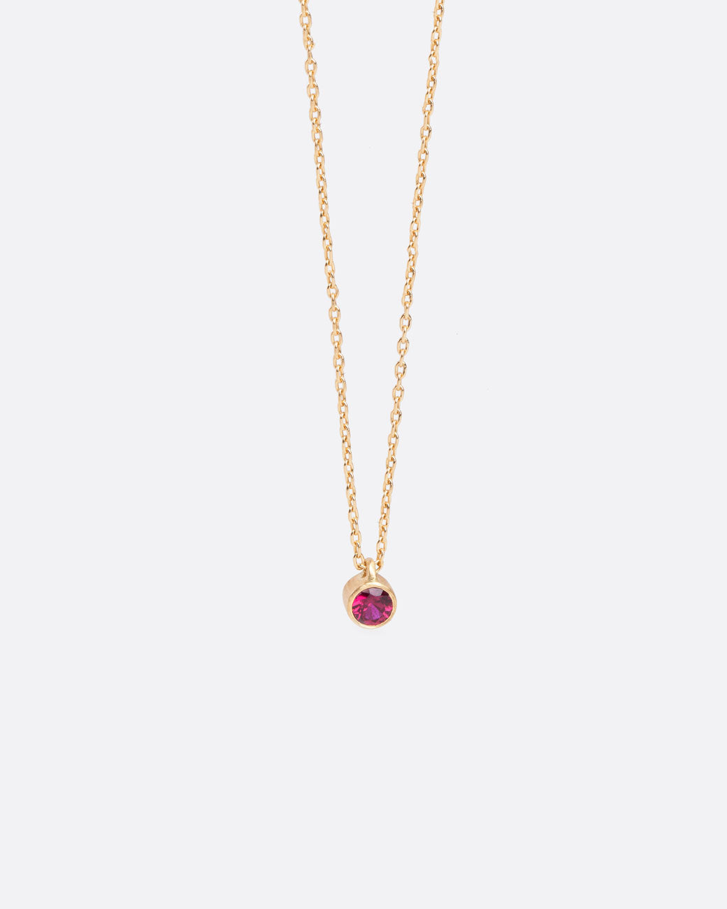 small ruby is bezel set in yellow gold on a 16 inch chain