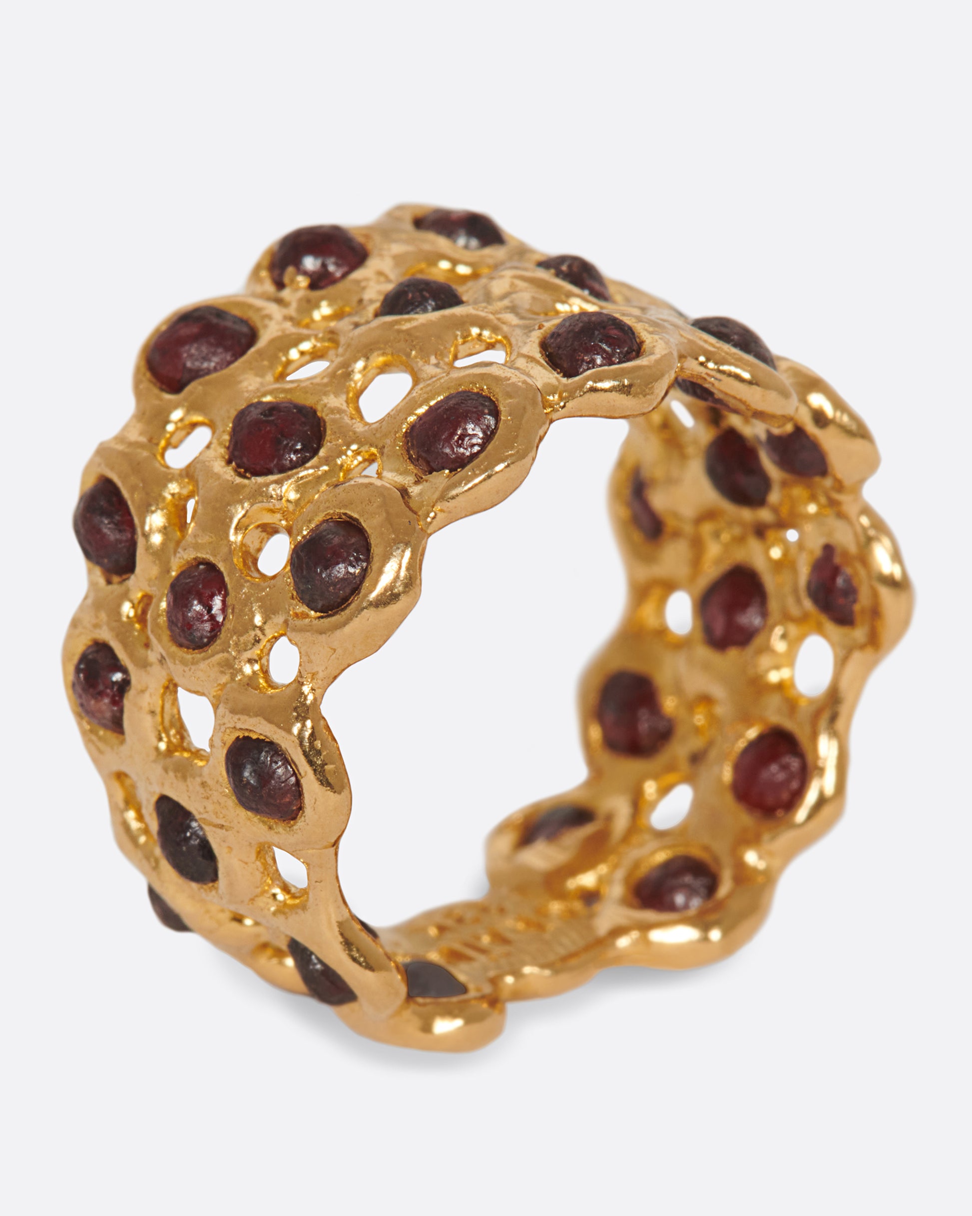 A ring made of a web of dark red garnet nuggets set in high karat gold bezels.