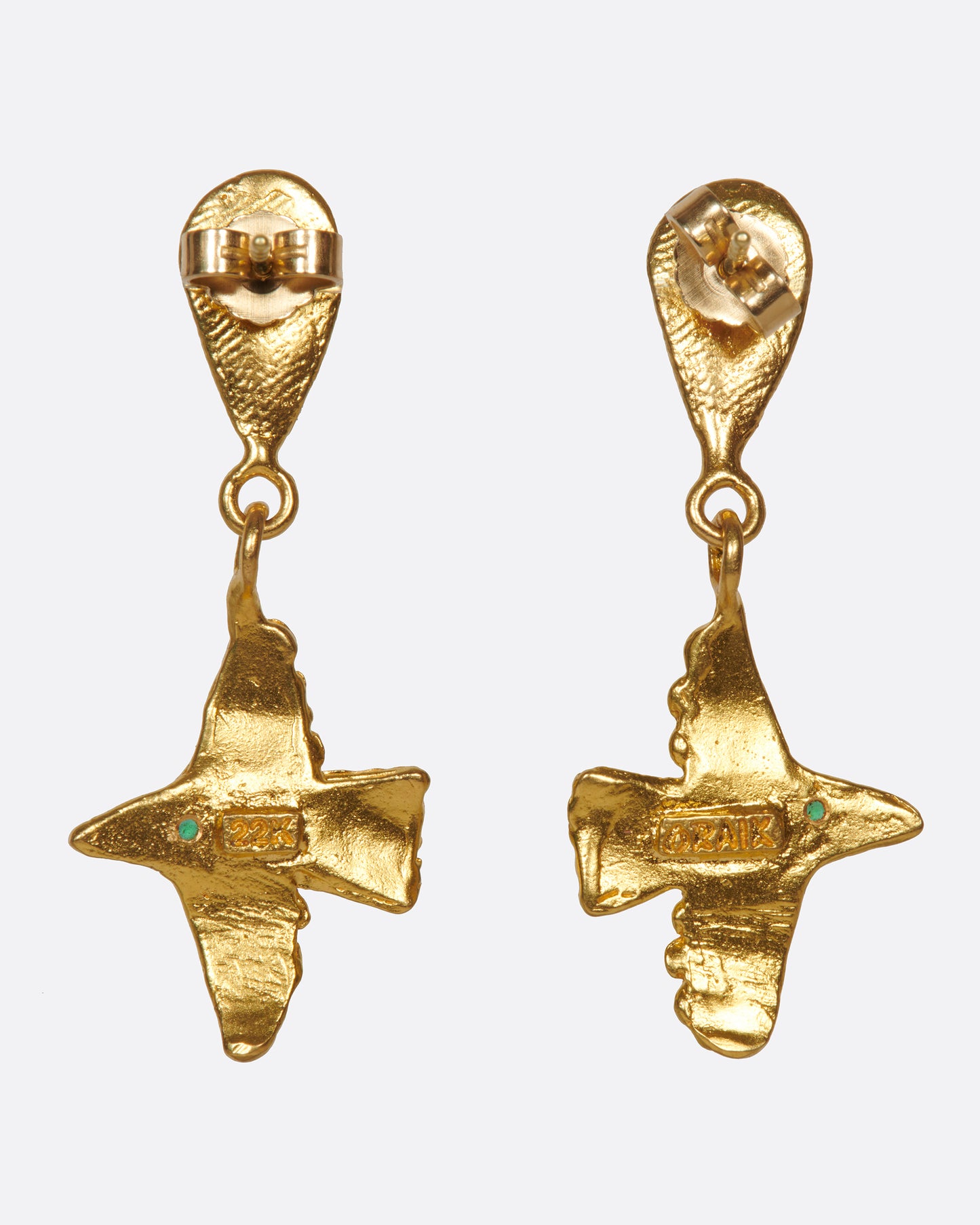 A pair of high karat gold drop earrings with flying birds and emerald eyes.