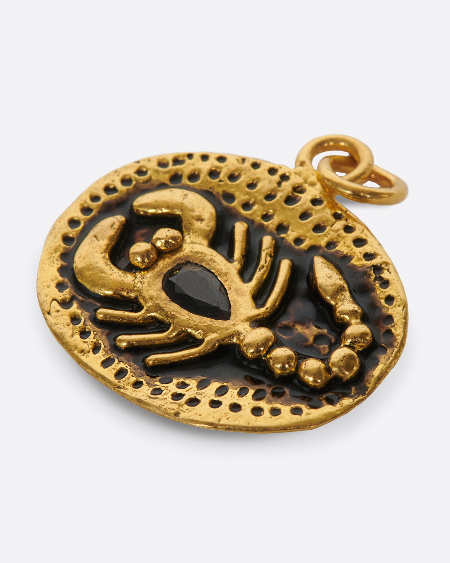 An oval gold pendant featuring a hand-sculpted scorpion with a pear shaped black sapphire body.