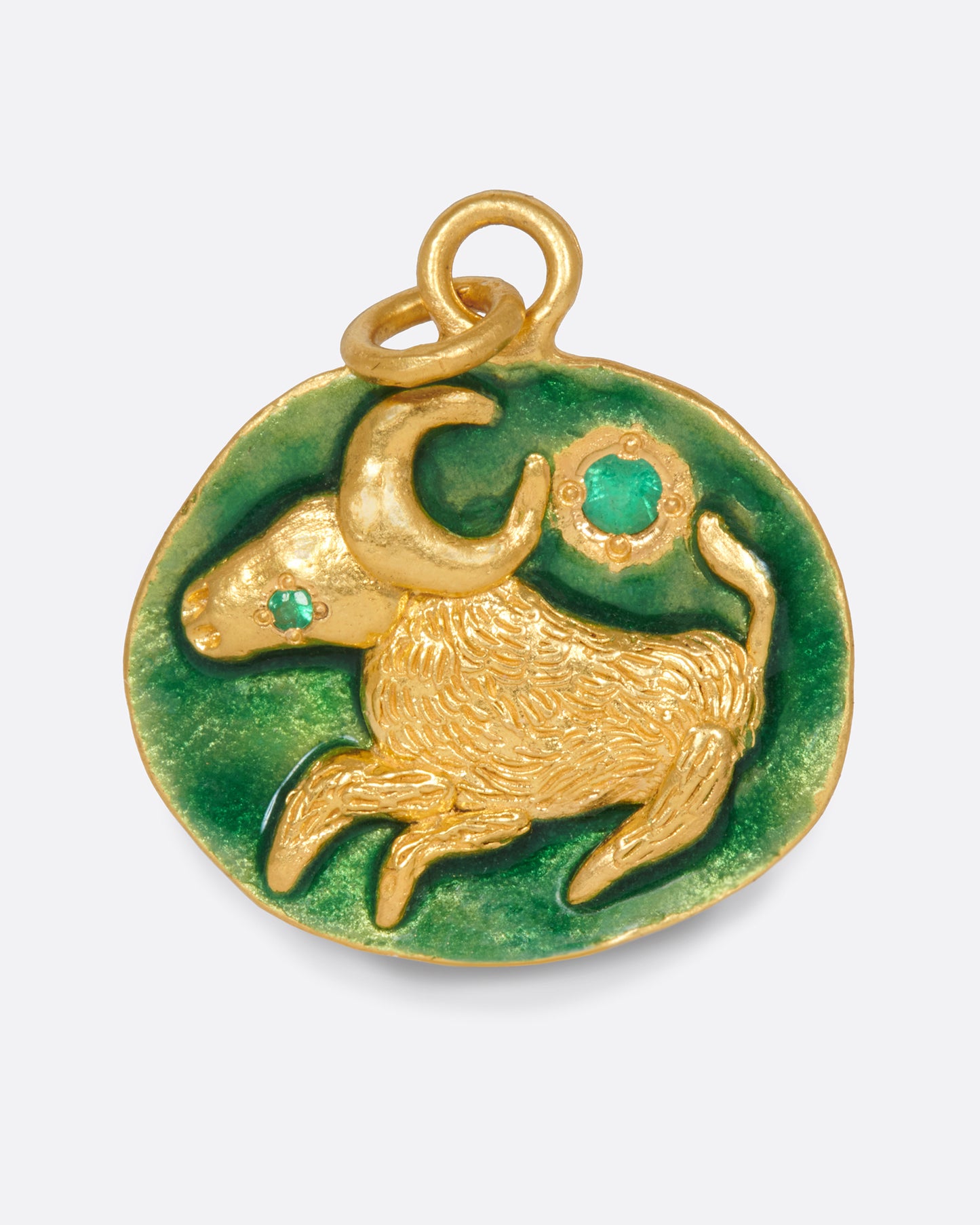 A slightly asymmetrical, circular pendant with a Taurus bull and emerald accents.