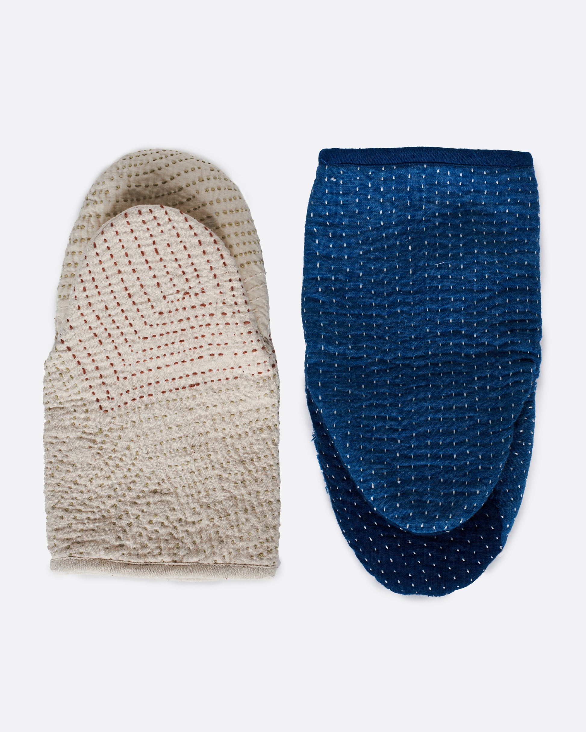 A pair of hand stitched oven mitts; one blue and one ivory.