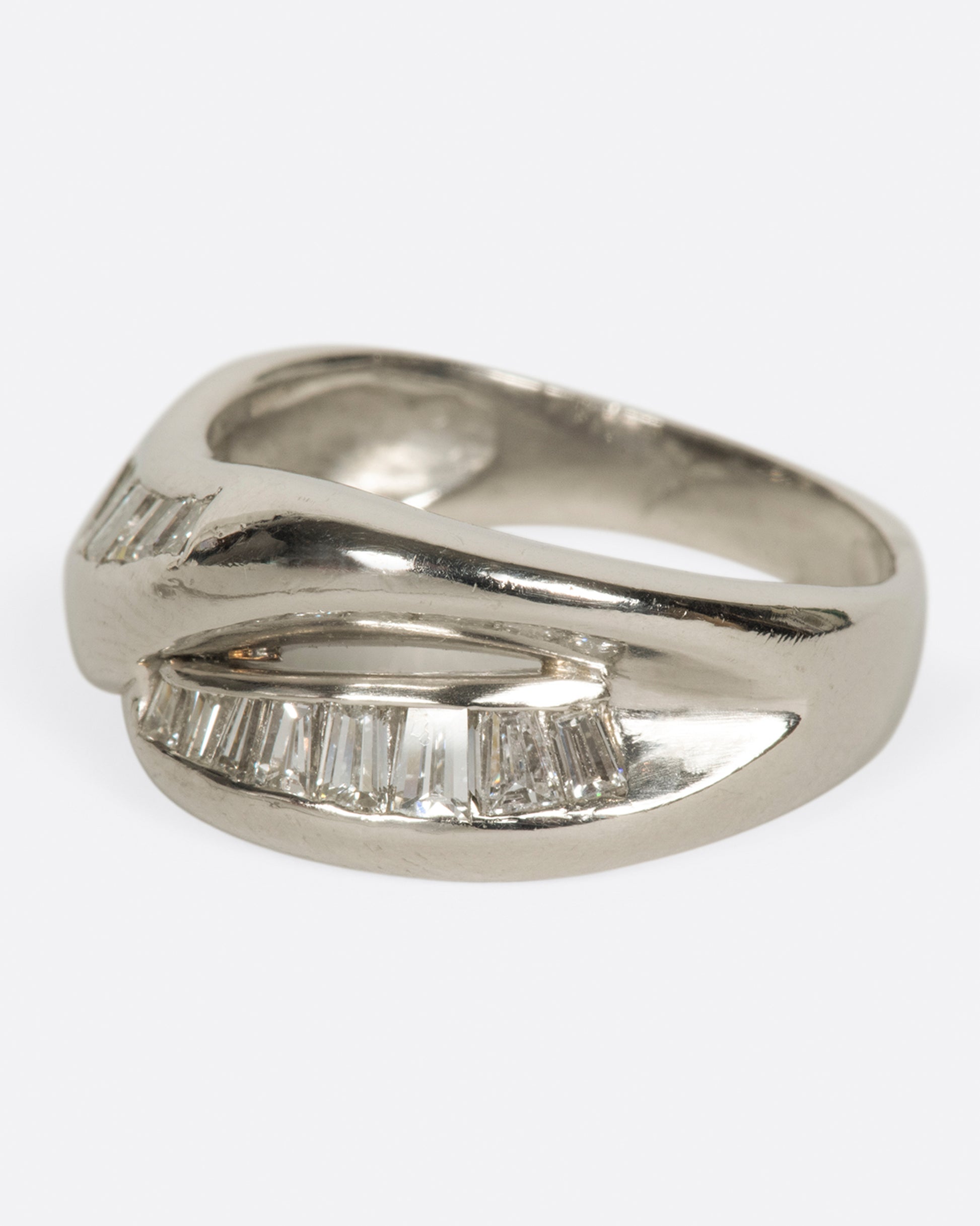 A platinum ring with two arches, lined with baguette diamonds.