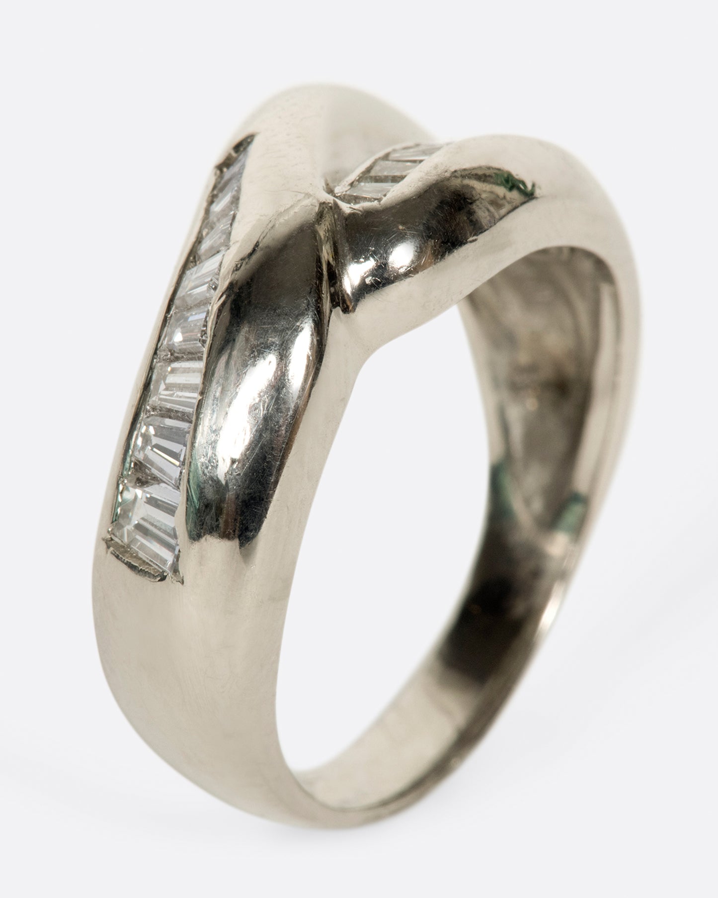 A platinum ring with two arches, lined with baguette diamonds.