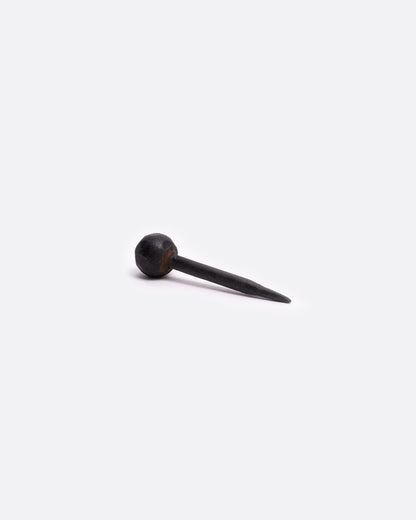 A single round head iron nail. Shown lying on its side.