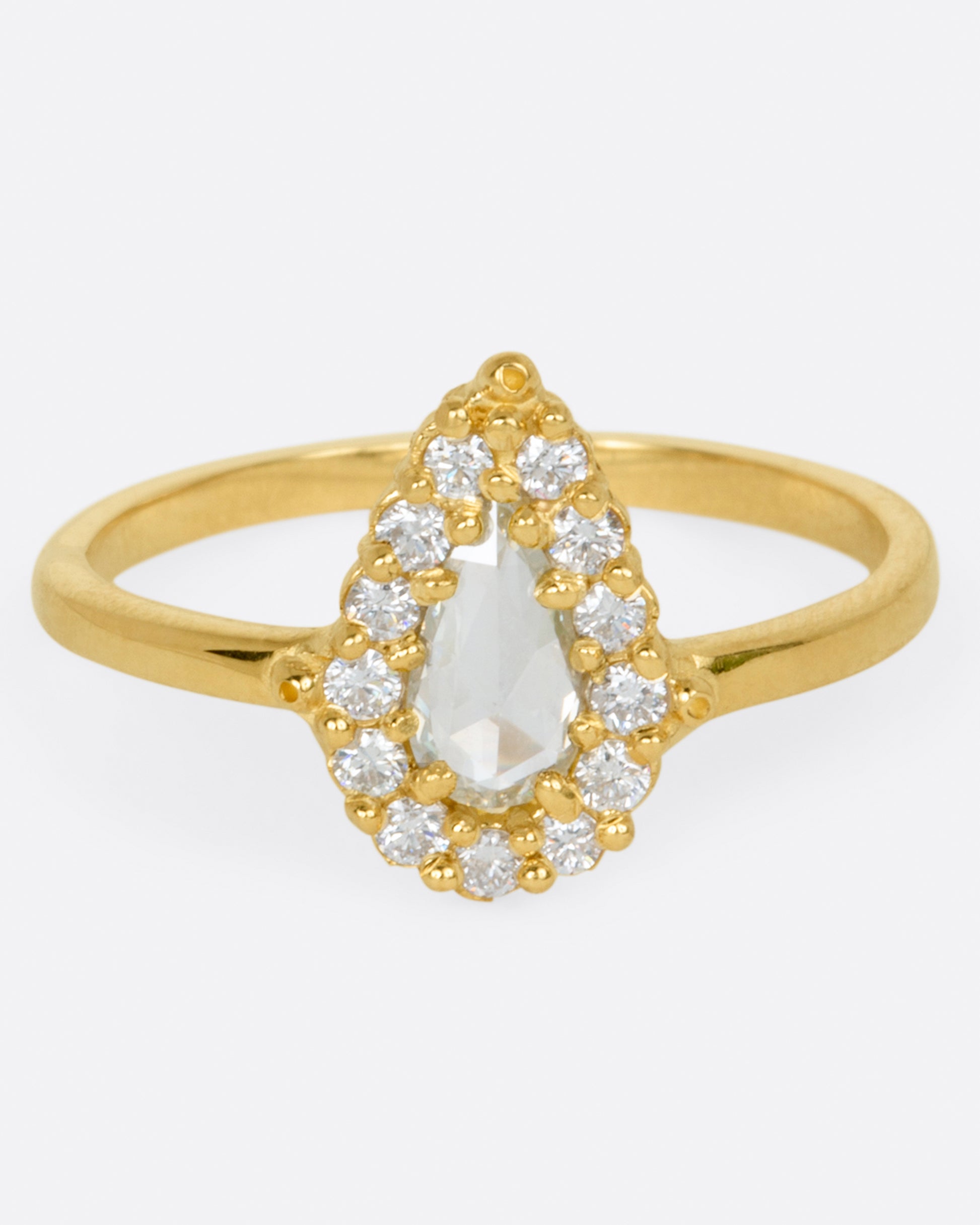 A light champagne, rose cut, pear shaped diamond ring with a round diamond halo.