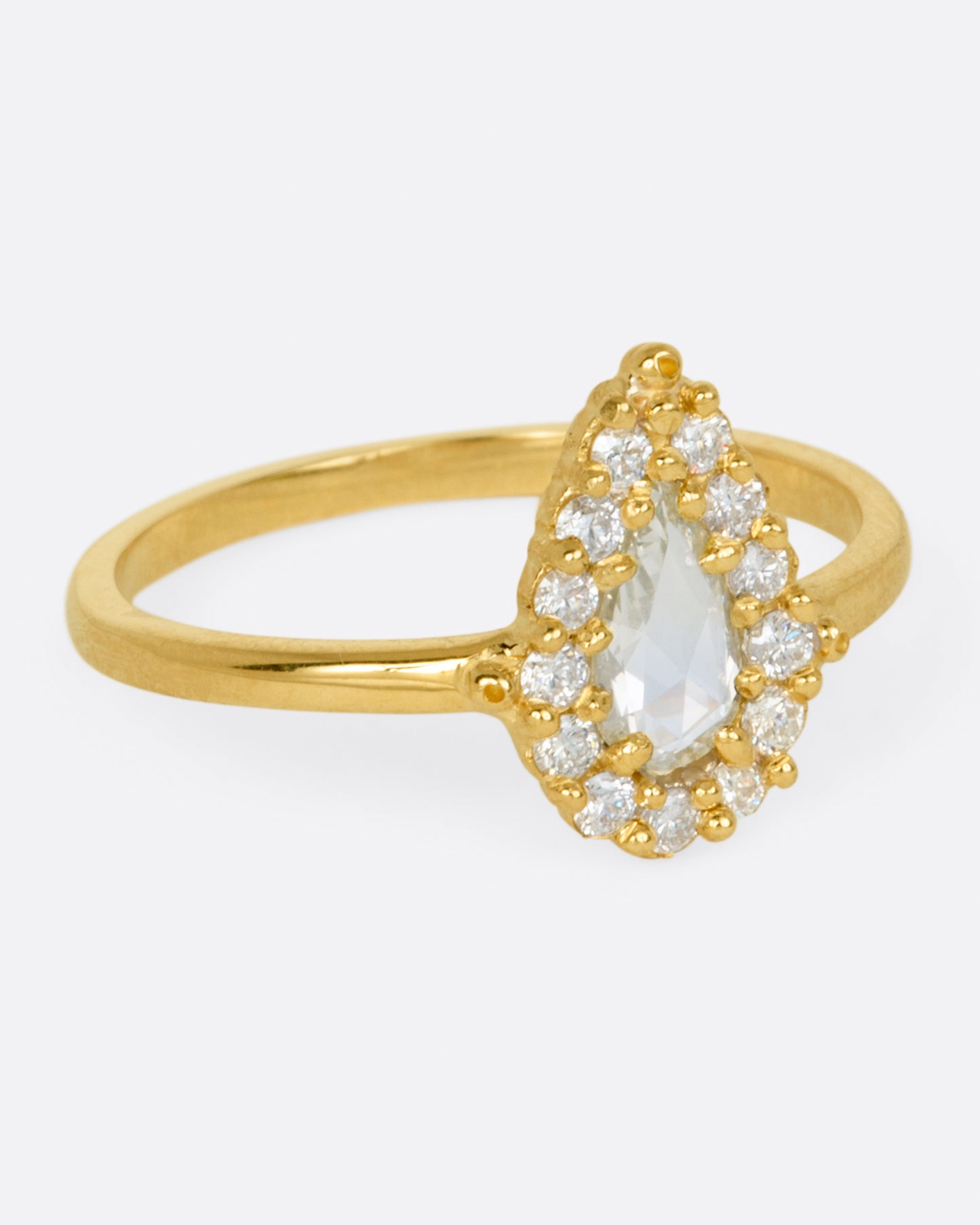 A light champagne, rose cut, pear shaped diamond ring with a round diamond halo.