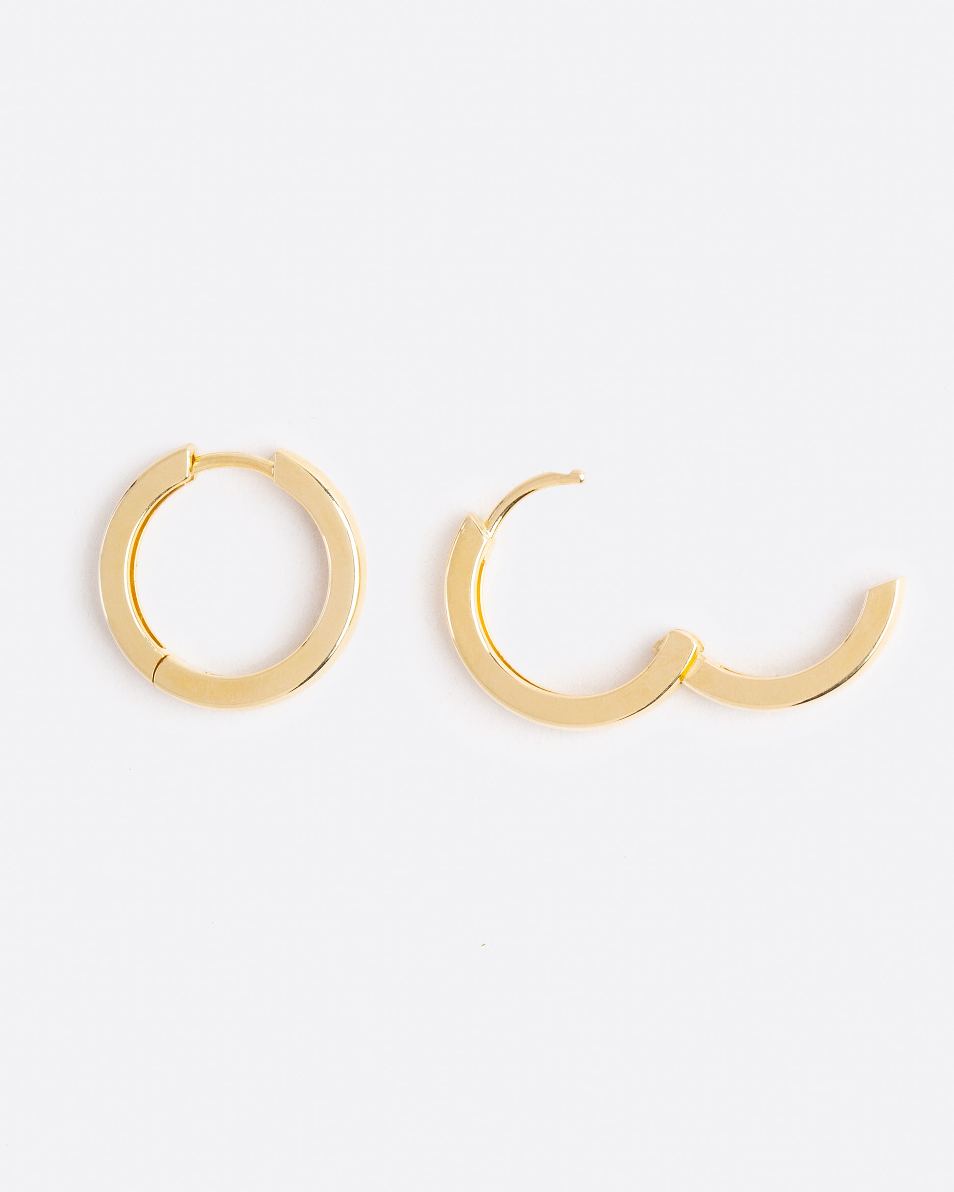 birds eye view of yellow gold hoop earrings, one of them is open