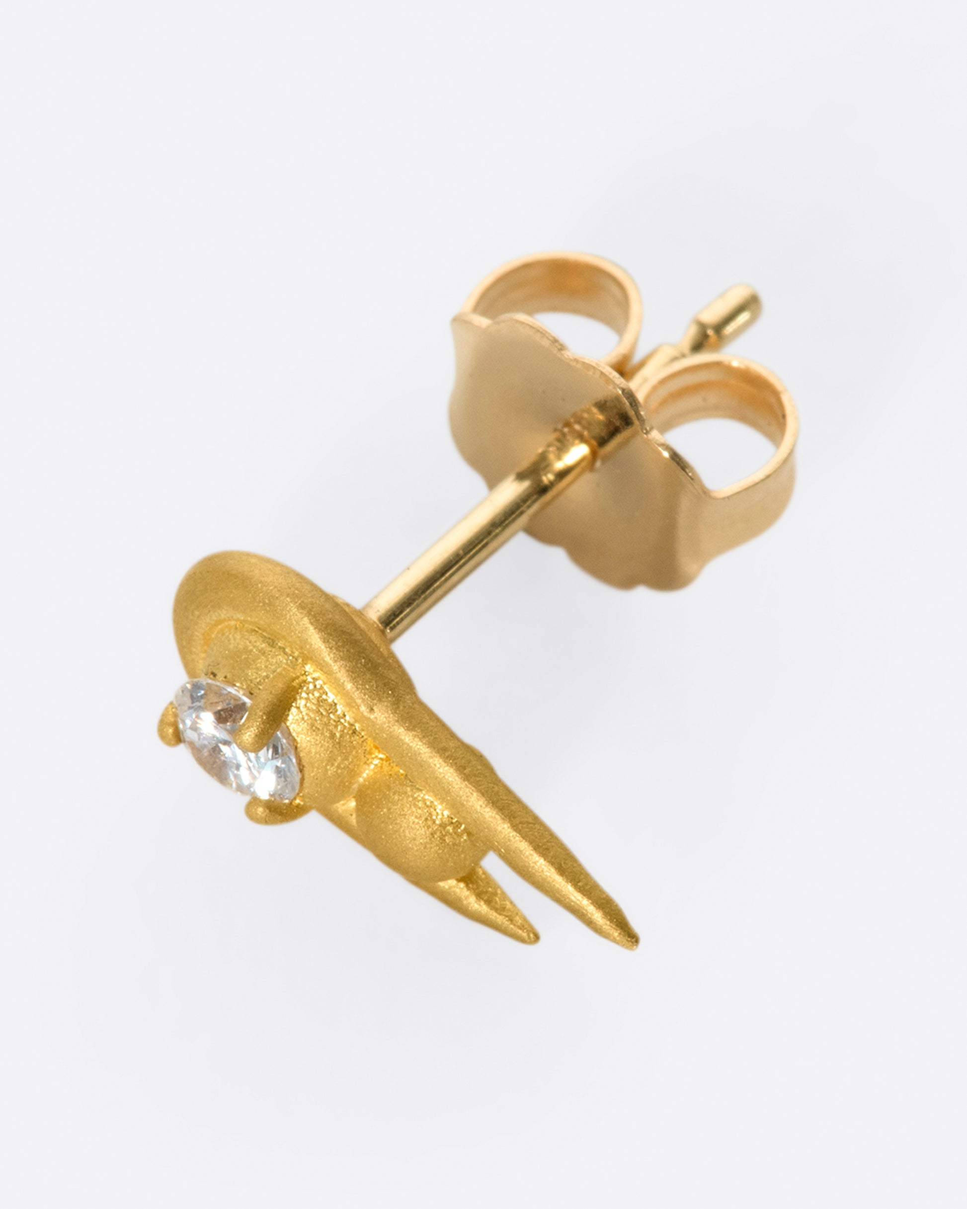 A curved high karat gold earring with a stacked sphere and brilliant cut diamond.