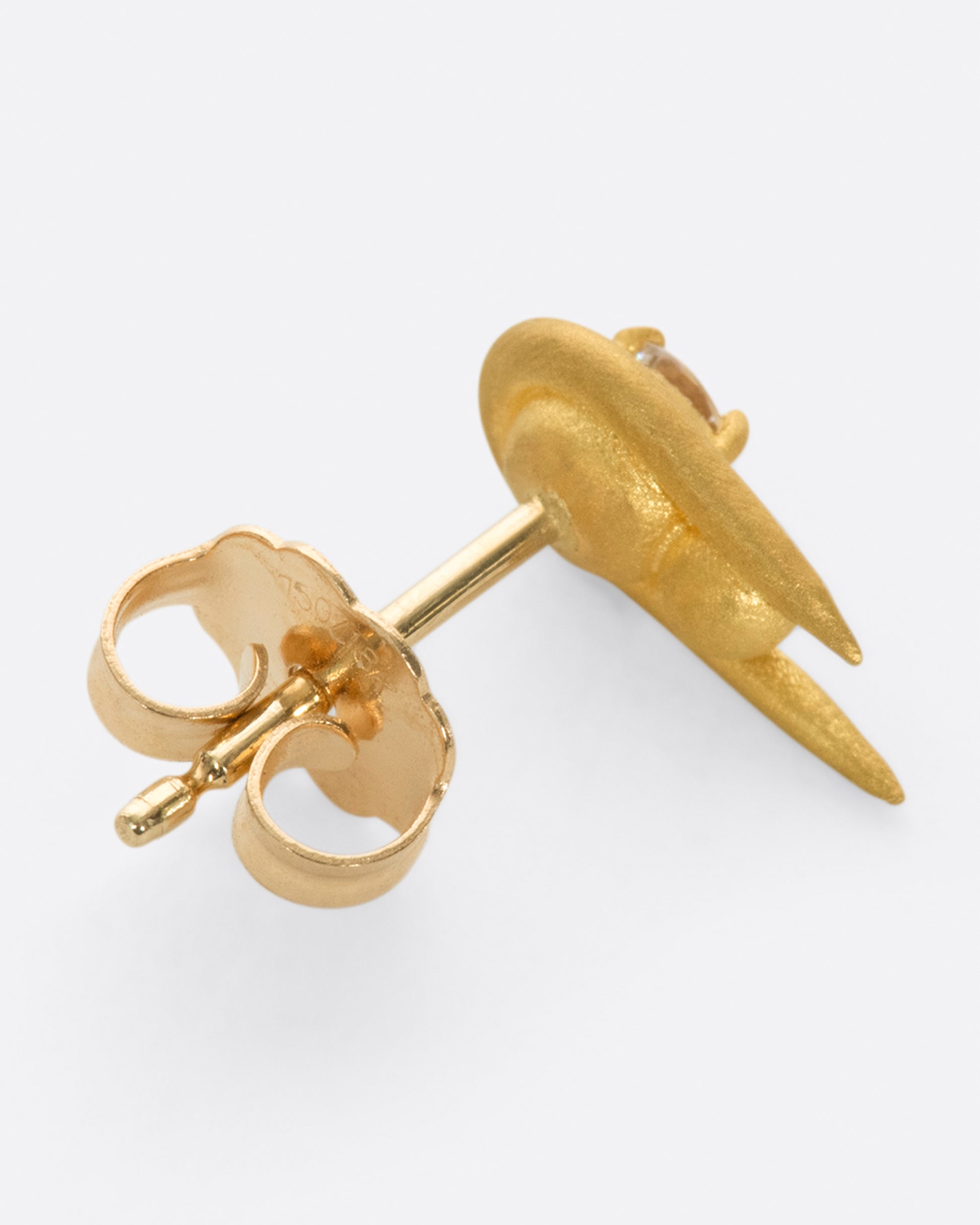 A curved high karat gold earring with a stacked sphere and brilliant cut diamond.