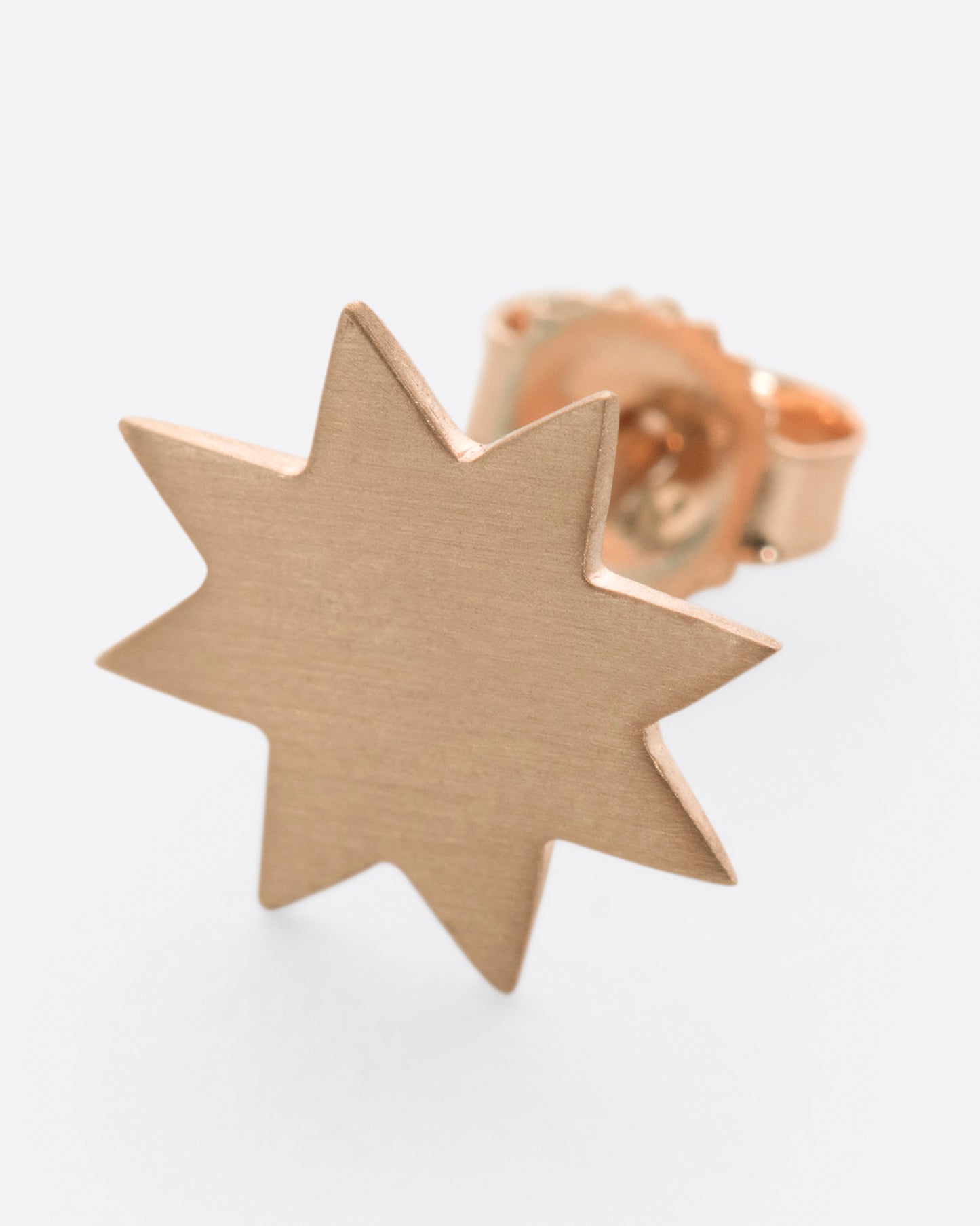 A brushed metal, pale pink eight-point star earring.