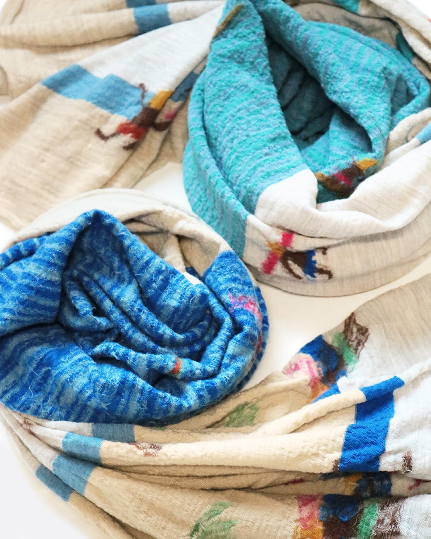 A compressed wool scarf with a fun pattern of surfers on a sandy beach.