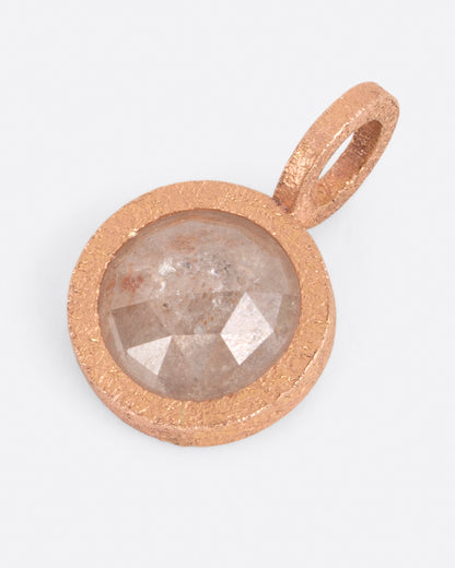 A pendant with a round icy gray diamond set in rose gold. Shown lying flat from the front.